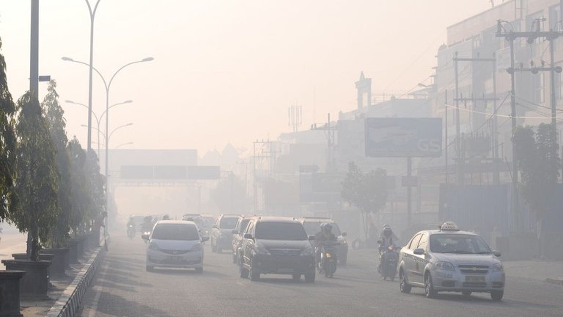 Commuters travel on a road blanketed by haze due to nearby forest fires, in Pekanbaru city, capital of Riau province on Sumatra island on June 19, 2013. Indonesia plans to use weather changing technology to try to unleash torrents of rain and extinguish raging fires on Sumatra island that have cloaked neighbouring Singapore in thick haze, an official said Wednesday.
