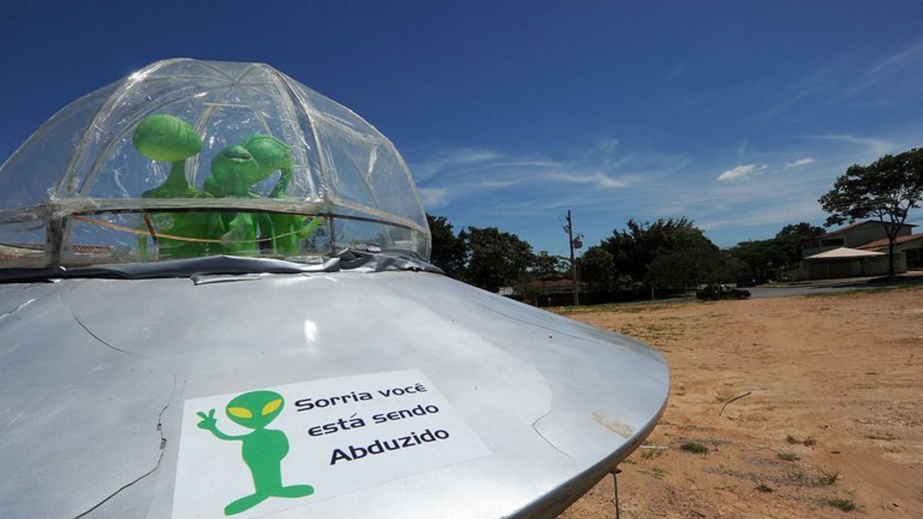 File picture shows a mock UFO with a sign reading "Smile, you are being abducted" north of Brasilia, December 2012. Britain's defence ministry shut down its UFO unit four years ago after concluding that extra-terrestrials likely did not exist, and in any case did not pose a threat, previously secret files released on Friday showed.
