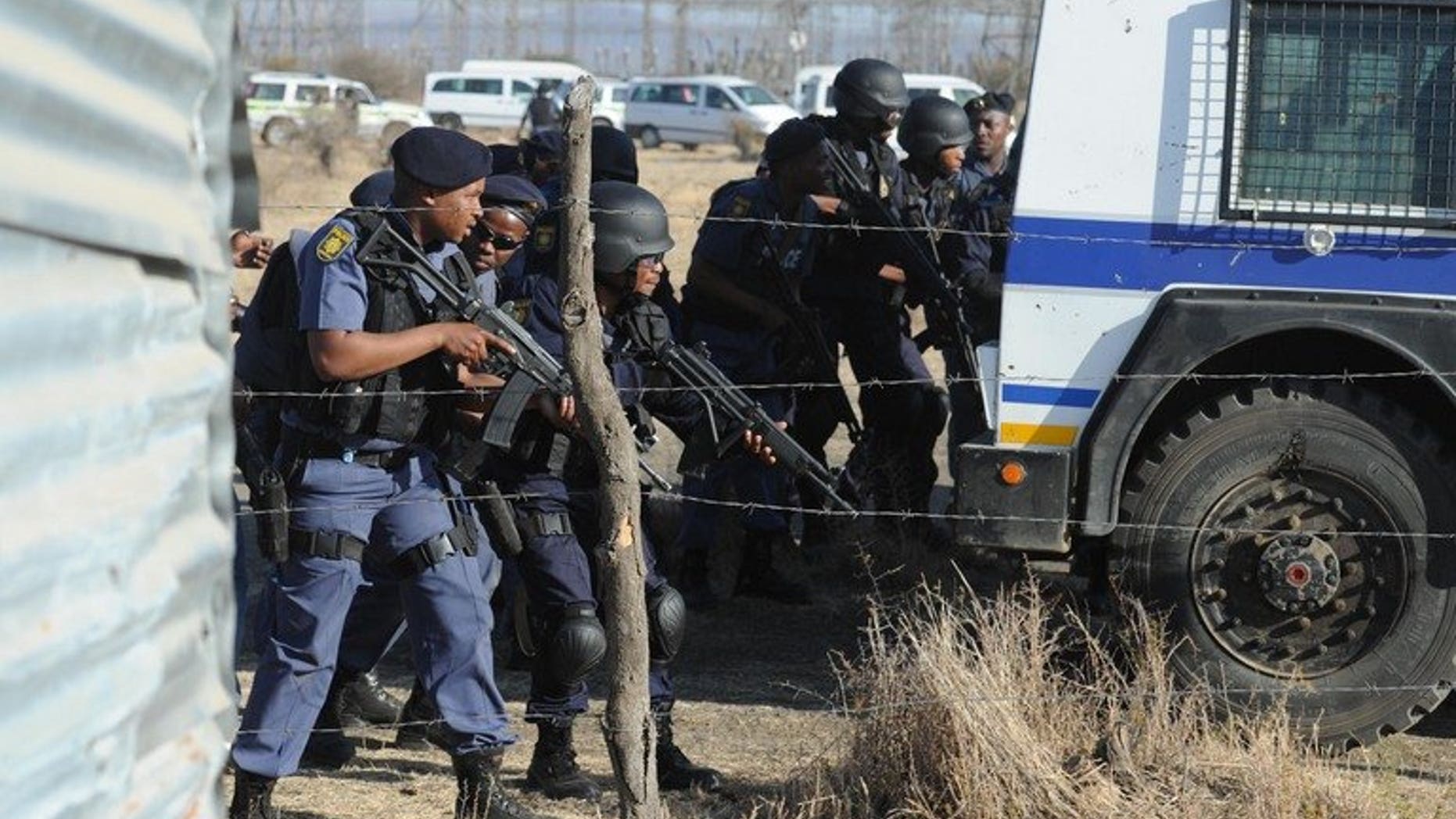 Police officers look at protesting miners near a platinum mine in Marikana on August 16, 2012. South Africa's Marikana commission adjourned Friday with major questions remaining about how police came to shoot dead 34 miners and amid growing concerns about the inquest itself.