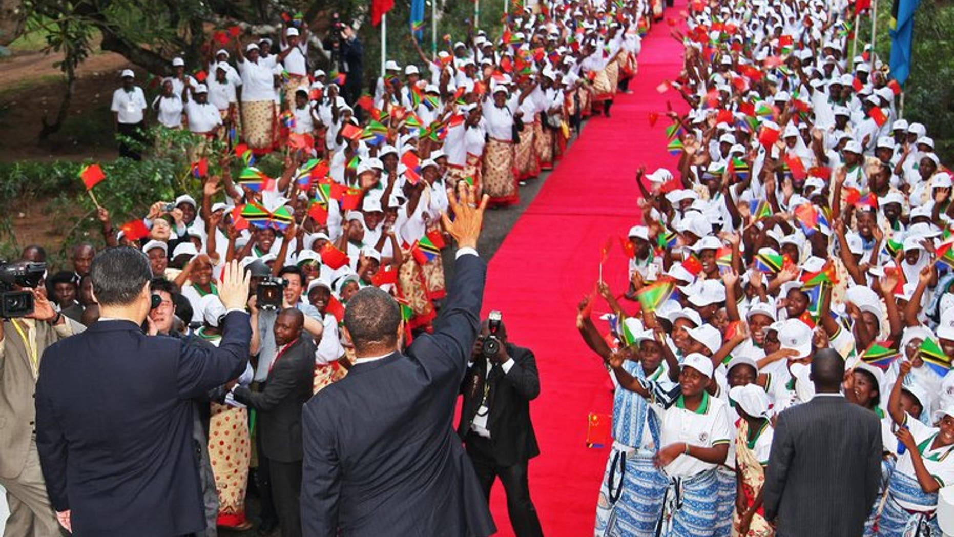 Chinese President Xi Jinping (L) and Tanzanian President Jakaya Kikwete (R) wave to crowds in Dar Es Salaam on March 24, 2013. World leaders visit Africa relatively little, but Tanzania is preparing to host US President Barack Obama just three months since a state visit the Chinese leader.
