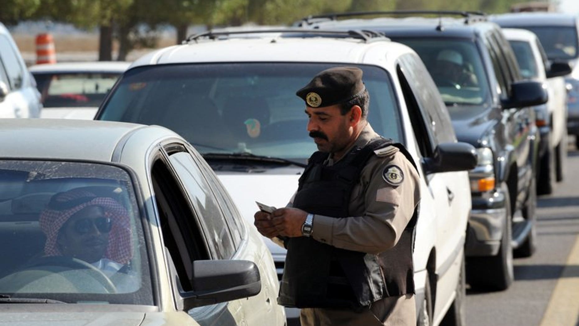 A Saudi policeman checks the ID card of a driver at a checkpoint in the mostly Shiite Qatif region of Eastern Province on November 25, 2011. A young man died on Saturday in Saudi Arabia's restive Shiite-populated region of Qatif, police said, saying he had been found in his car after unknown gunmen opened fire at patrolmen in the area.