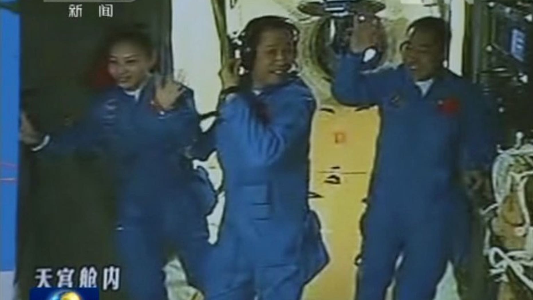 Chinese astronauts (left to right) Wang Yaping, Nie Haisheng and Zhang Xiaoguang waving after they entered the Tiangong-1 space module, on June 13, 2013. The three astronauts on China's longest manned space mission have succeeded in manually docking their spacecraft with a module orbiting Earth.