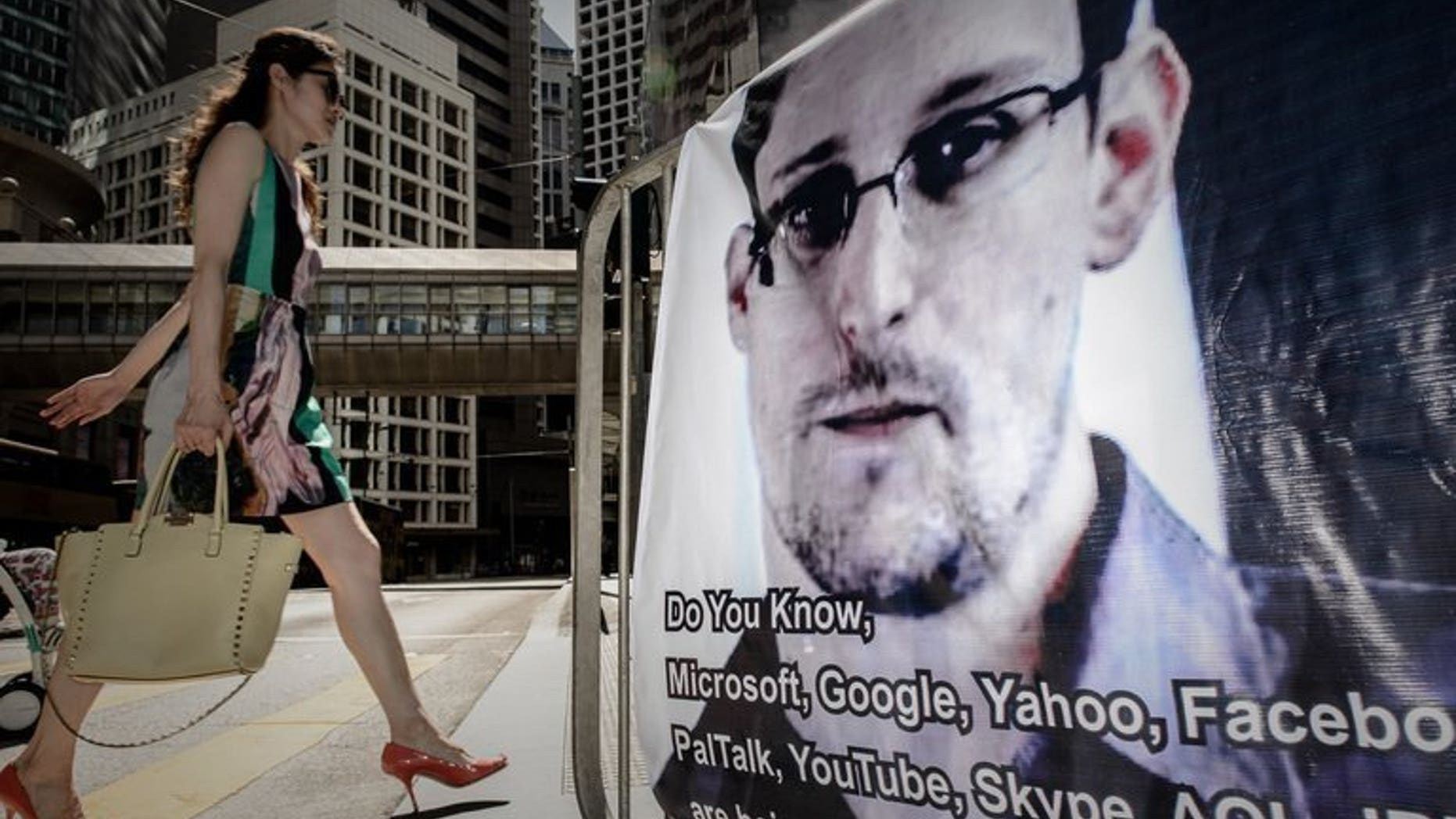 A woman walks past a banner displayed in support of former US spy Edward Snowden in Hong Kong on June 18, 2013. Snowden has requested asylum in Ecuador, the Ecuadoran foreign minister said Sunday, as he seeks to escape US justice for revealing secrets of a vast phone and Web surveillance drive.