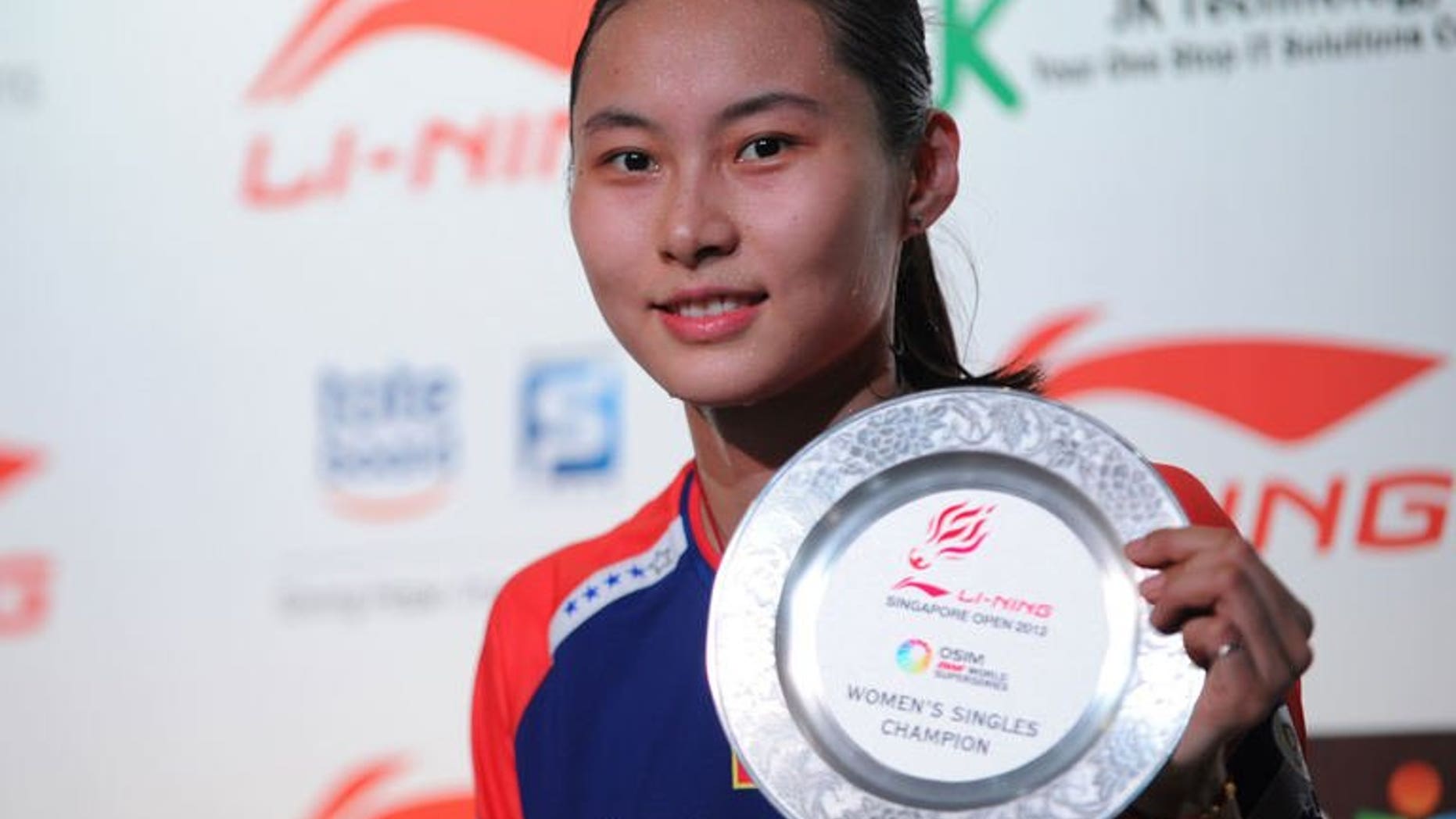 China's Wang Yihan poses with the plaque after winning against compatriot Li Xuerui during their women's singles final badminton match at the Singapore Open on June 23, 2013. Wang won 21-18, 21-12.