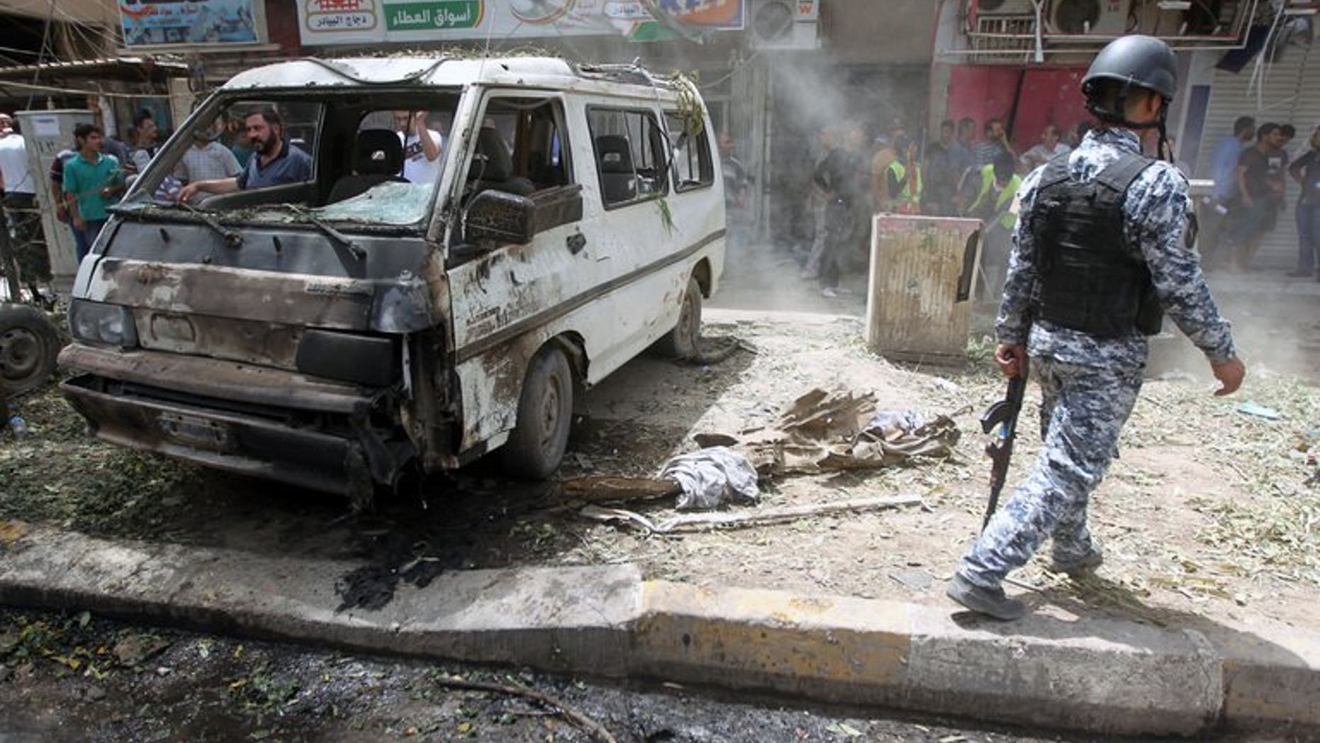 An Iraqi policeman walks past a damaged vehicle on the scene of a car bomb attack in Baghdad's commercial area of Karradah on May 30, 2013. A series of car bombs across Baghdad killed 15 people and wounded 65 on Monday, officials said, the latest in deadly violence that has sparked fears of a revival of full-blown sectarian war.