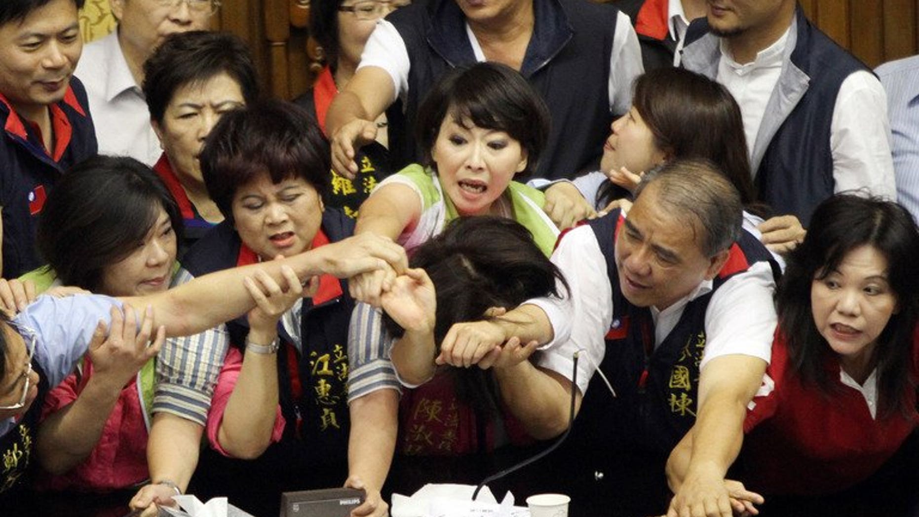 Legislators from Taiwan's ruling Kuomintang party and opposition try to seize the podium in parliament on June 25, 2013. Fighting broke out in Taiwan's parliament Tuesday as legislators scuffled and threw coffee during a debate on whether a controversial capital gains tax on share trading should be revised less than a year after it was brought in.