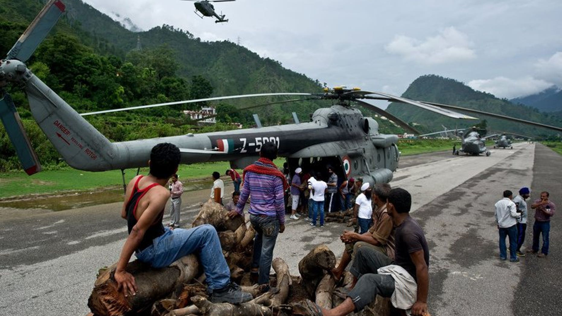 Indian workers wait to offload wood to be carried by an Indian Air Force (IAF) helicopter at Gauchar Airfield on June 25, 2013, ahead of cremation preparations for flood victims in the northern state of Uttarakhand at Kedarnath. Indian officials stepped up Tuesday efforts to prevent an outbreak of disease in the northern Himalayan region devastated by landslides and flash floods.