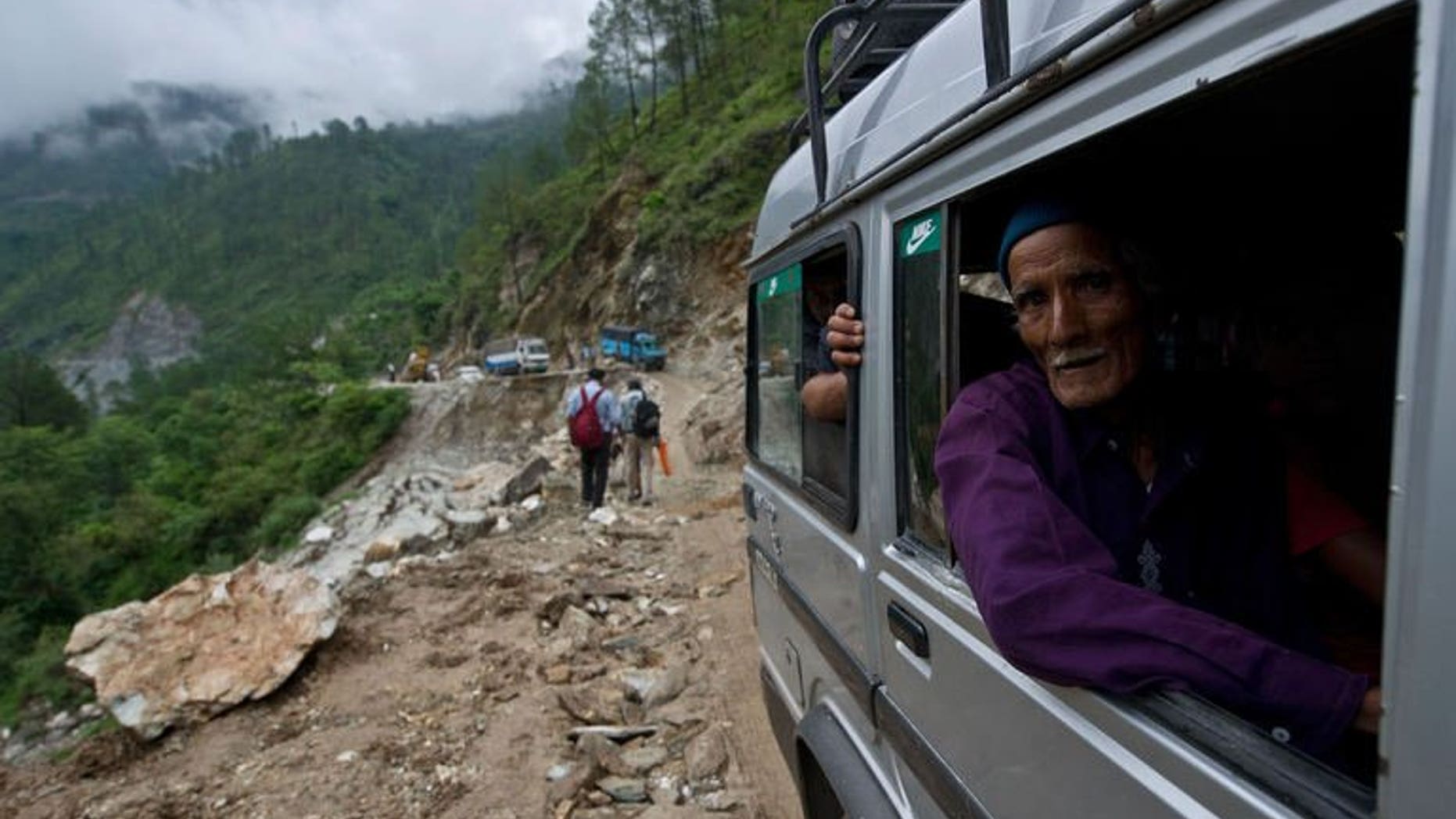 An elderly Indian man looks out as he drives past a damaged section of road between Rudraprayag and Gauchar, at Gauchar on June 25, 2013, after flash flooding hit the northern Indian state of Uttarakhand. An Indian television journalist reporting on the deadly floods that have swept northern India defended his decision on Tuesday to file a report while perched on a survivor's shoulders.