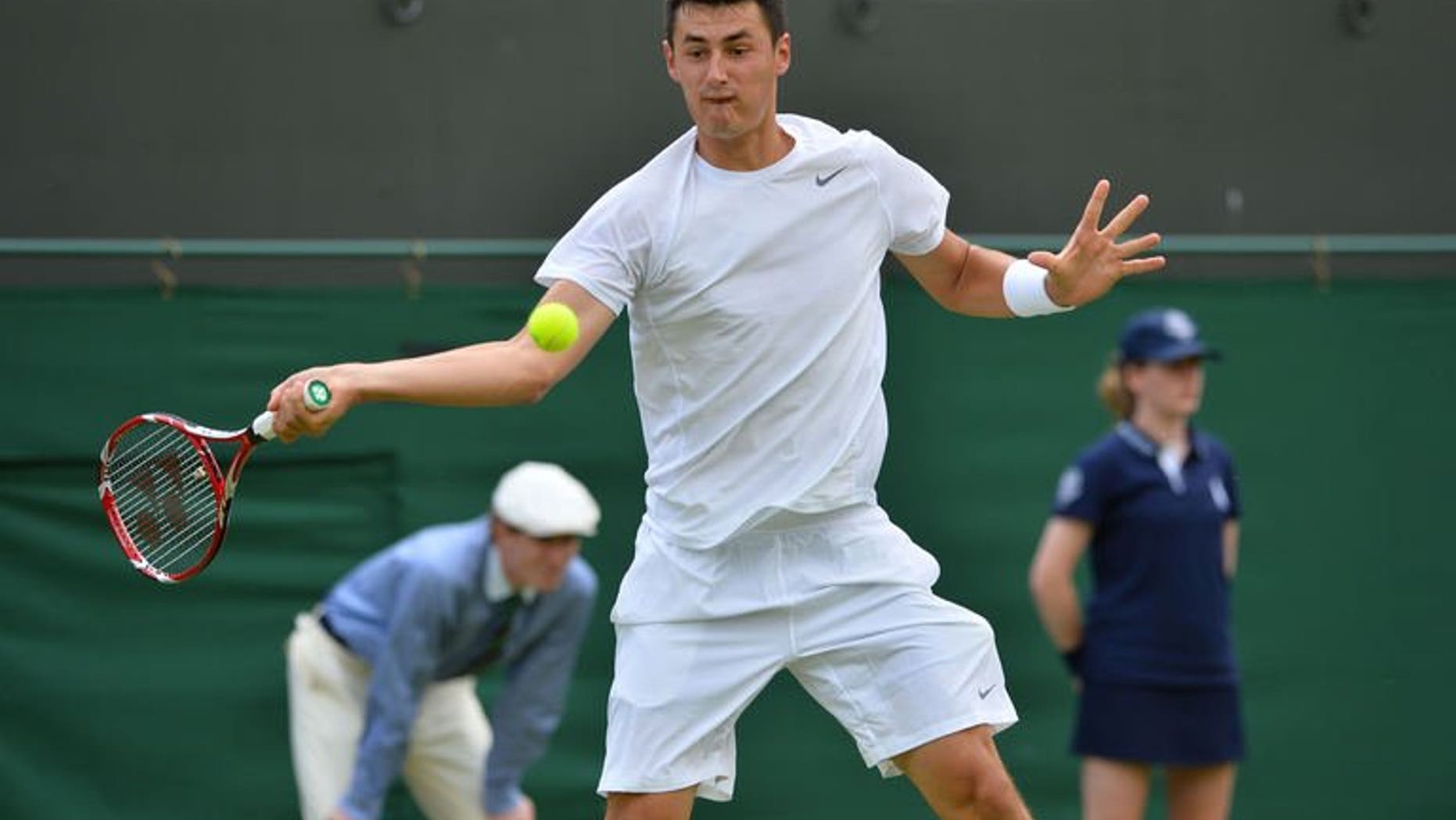 Australia's Bernard Tomic hits a return against US player Sam Querrey during their men's first round match on day two of the 2013 Wimbledon Championships tennis tournament at the All England Club in Wimbledon, southwest London, on June 25, 2013. Tomic blasted the ban on his father watching him at Wimbledon, accusing the men's tour of bad manners.