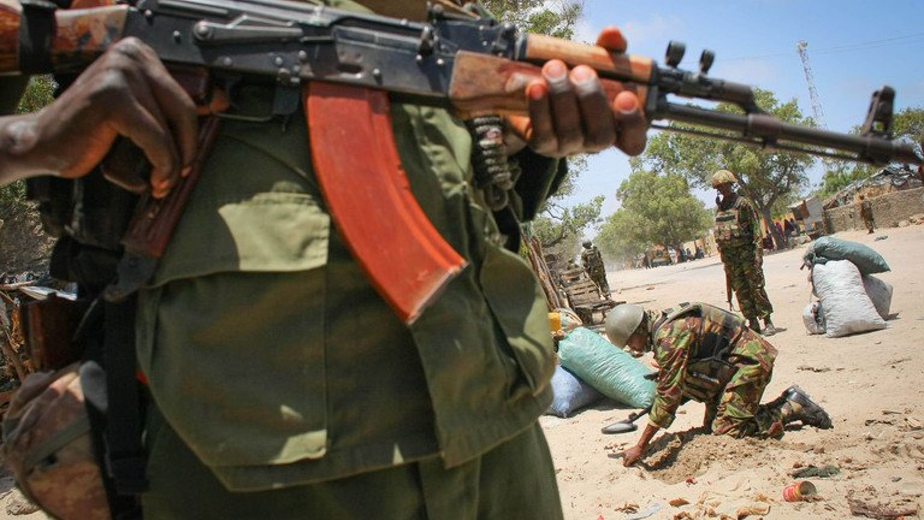 A fighter of the Ras Kimboni Brigade militia stands guard as a team searches for explosives in the Somali port city of Kismayo, on October 7, 2013. At least five people have been killed in clashes between rival Somali warlords fighting for control of the city, residents said.