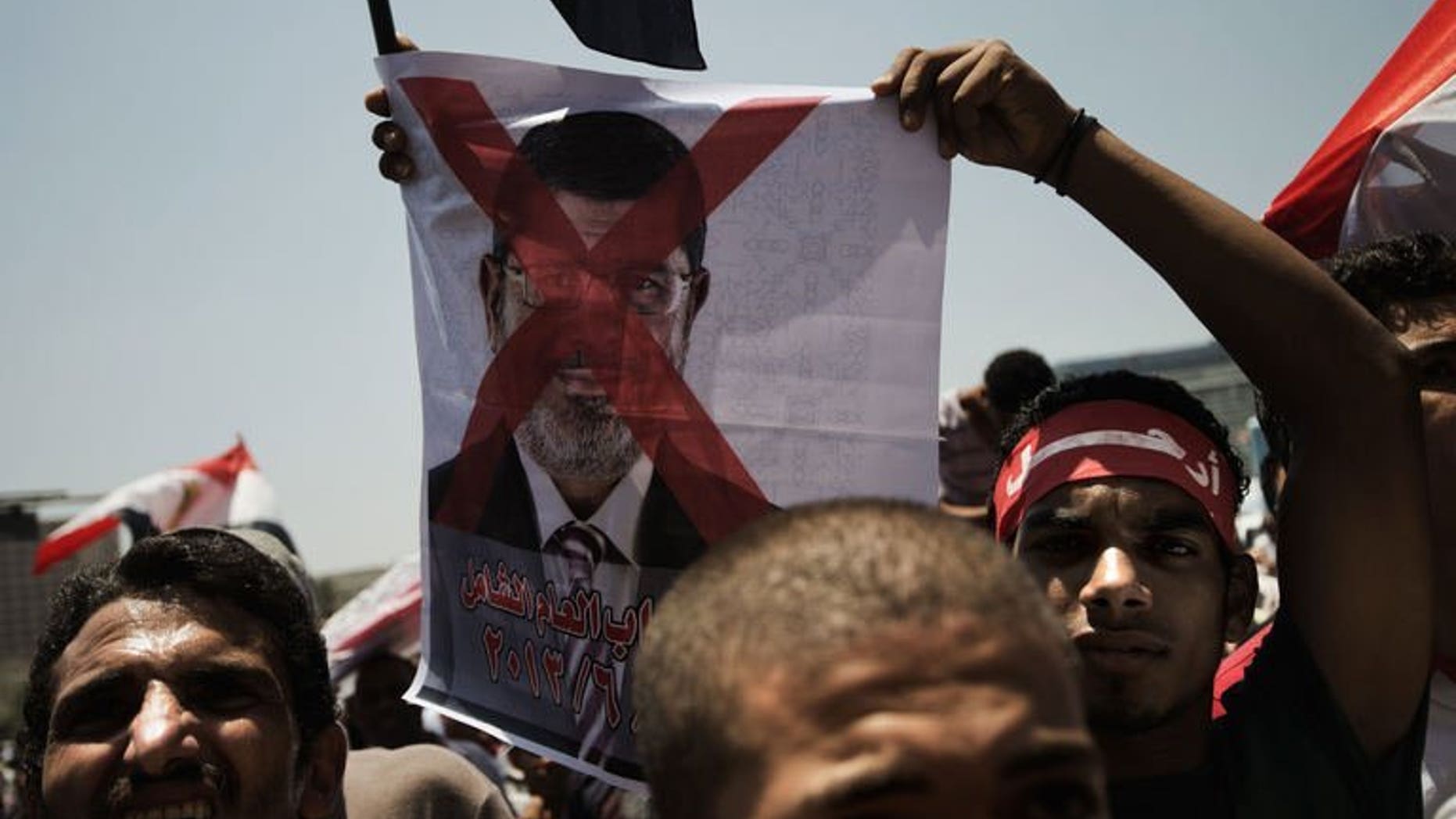 An Egyptian opposition supporter holds a crossed-out picture of President Mohammed Morsi in Cairo's landmark Tahrir Square on June 29, 2013.
