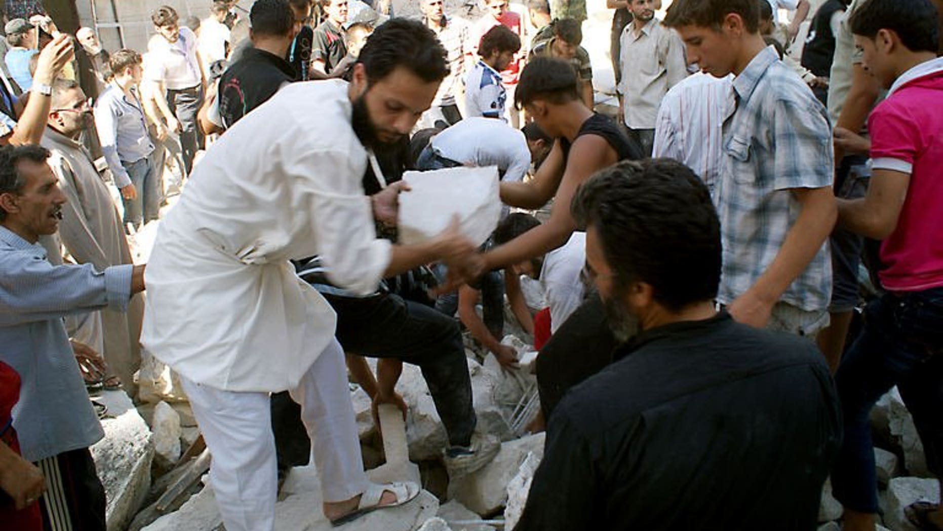 Rescuers and neighboors removes chunks of rubble from a partially collapsed building after a rocketed slammed into the side of a residential block located next to a mosque in Aleppo, Syria on June 29, 2013. The Gulf Arab nations and the European Union pledged Sunday to pool their efforts to help convene a peace conference on Syria, as they wrapped up a one-day ministerial meeting in Bahrain.