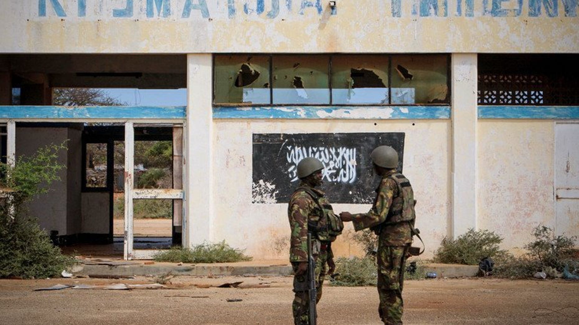 Photo released by the AU-UN Information Support Team on October 2, 2012 shows soldiers of the Kenyan contingent serving with the African Union Mission in Somalia near the black flag of the Al Qaeda-linked group Shebaab on the wall of Kismayo Airport. Somalia's government has demanded that Kenyan troops stationed in the volatile port city of Kismayo be replaced, accusing them of backing Shebab.