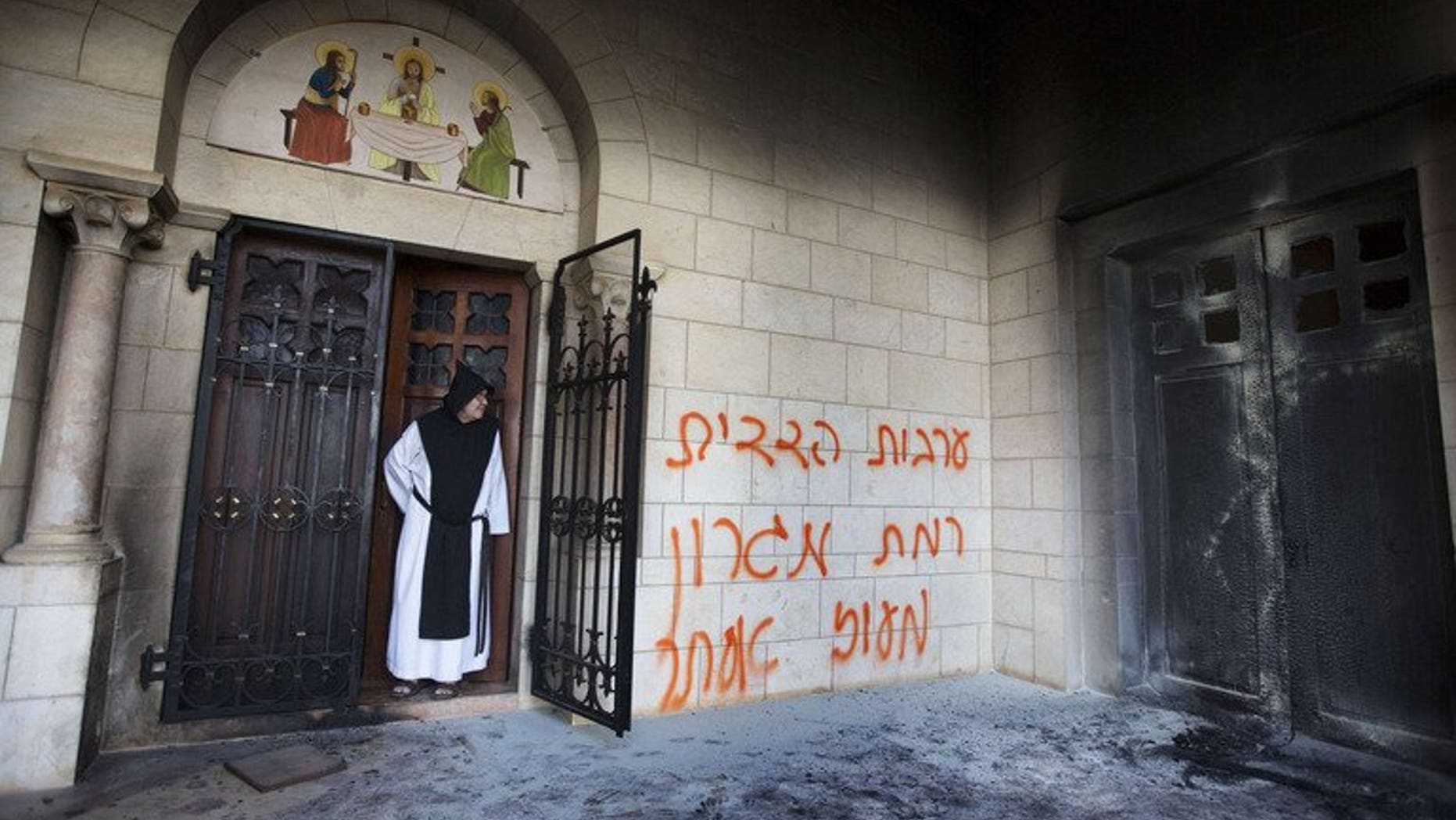 A picture taken on September 4, 2012 shows a Trappist monk looking at graffiti which was sprayed on the wall of the Latrun monastery. A court has extended the remand of an Israeli man arrested on suspicion of vandalising the Catholic monastery in an attack that shocked the Holy Land's religious and political establishment.