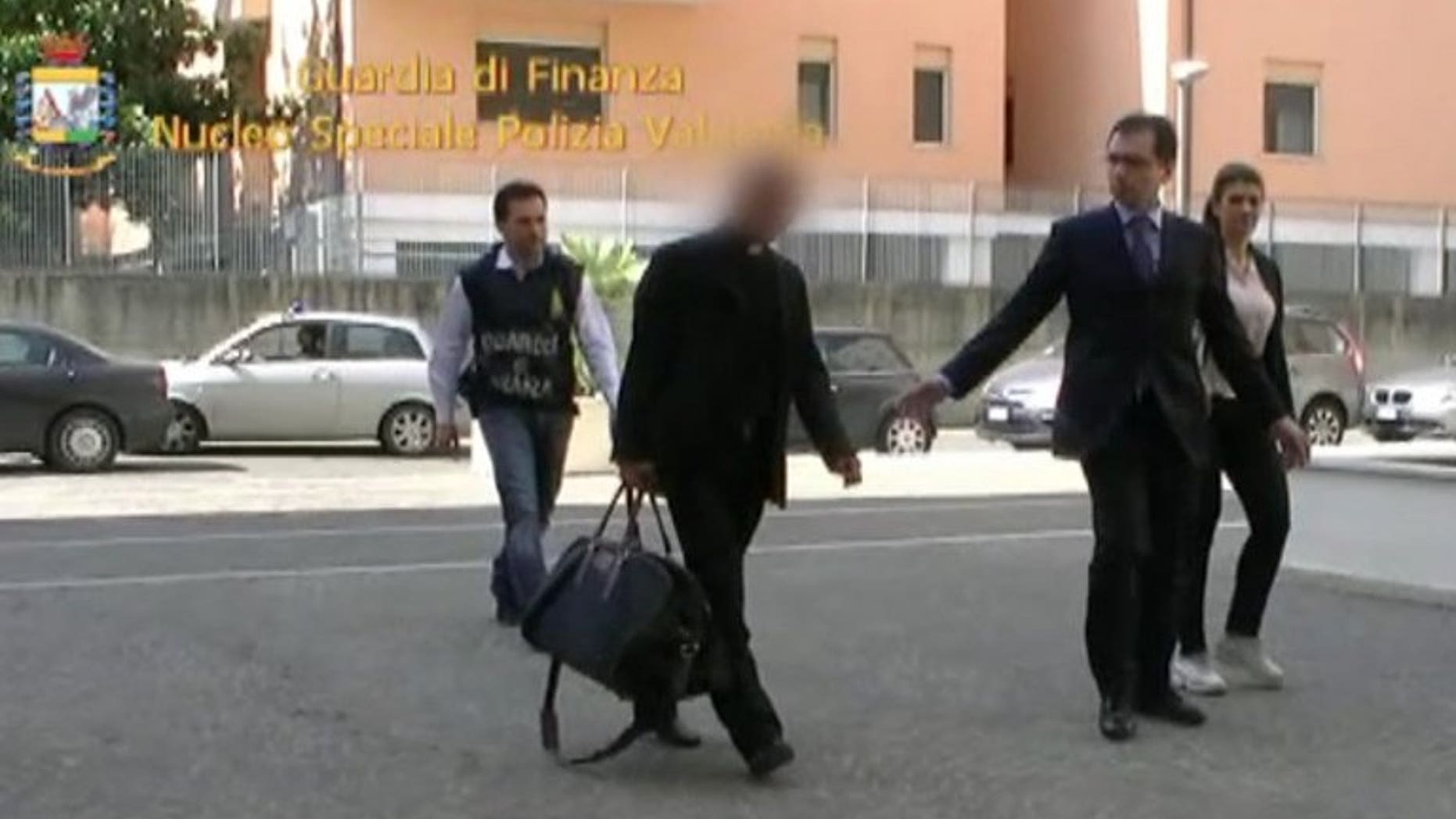 This handout picture taken from a video released by the Guardia di Finanzia Italian police on June 28, 2013 shows Nunzio Scarano (front left) being escorted by policemen after his arrest in Rome.