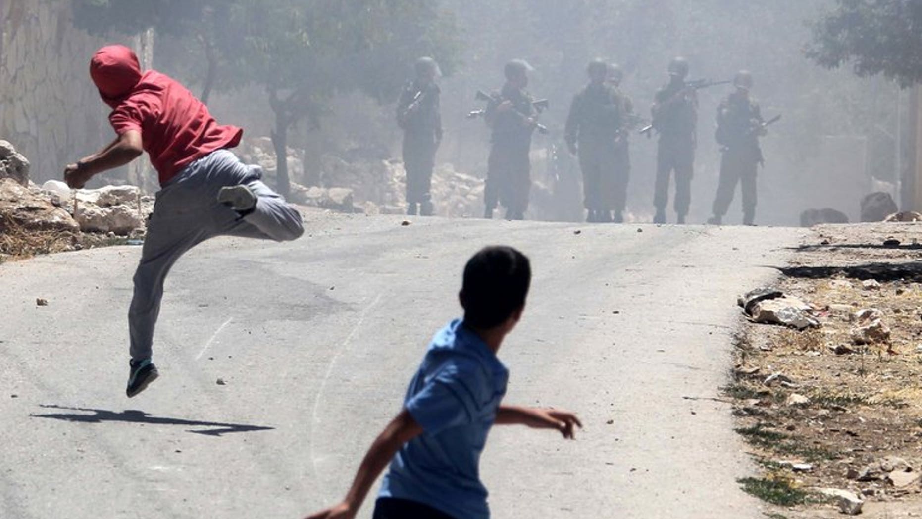 Palestinian protesters throw stones towards Israeli security forces during clashes near the West Bank city of Nablus, on June 28, 2013. A Palestinian teenager was knocked down and killed by an Israeli military jeep during overnight clashes in a village in the southern West Bank, Palestinian police and witnesses told AFP.