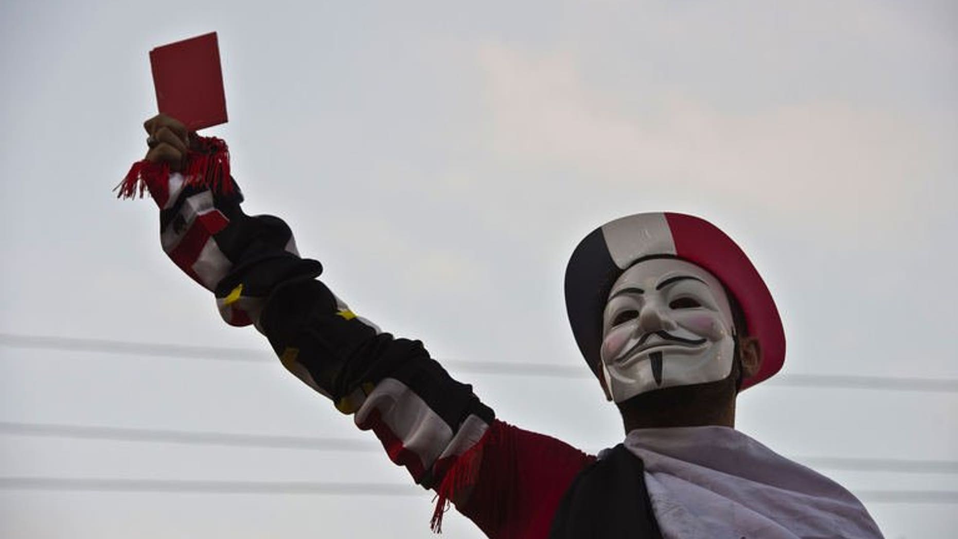 A protester wearing a Guy Fawkes mask holds up a red card as thousands of Egyptian demonstrators gather outside the presidential palace in Cairo, on July 1, 2013. US President Barack Obama has called President Mohamed Morsi to warn him that the voices of all Egyptians must be heard as a political crisis escalates, the White House said.