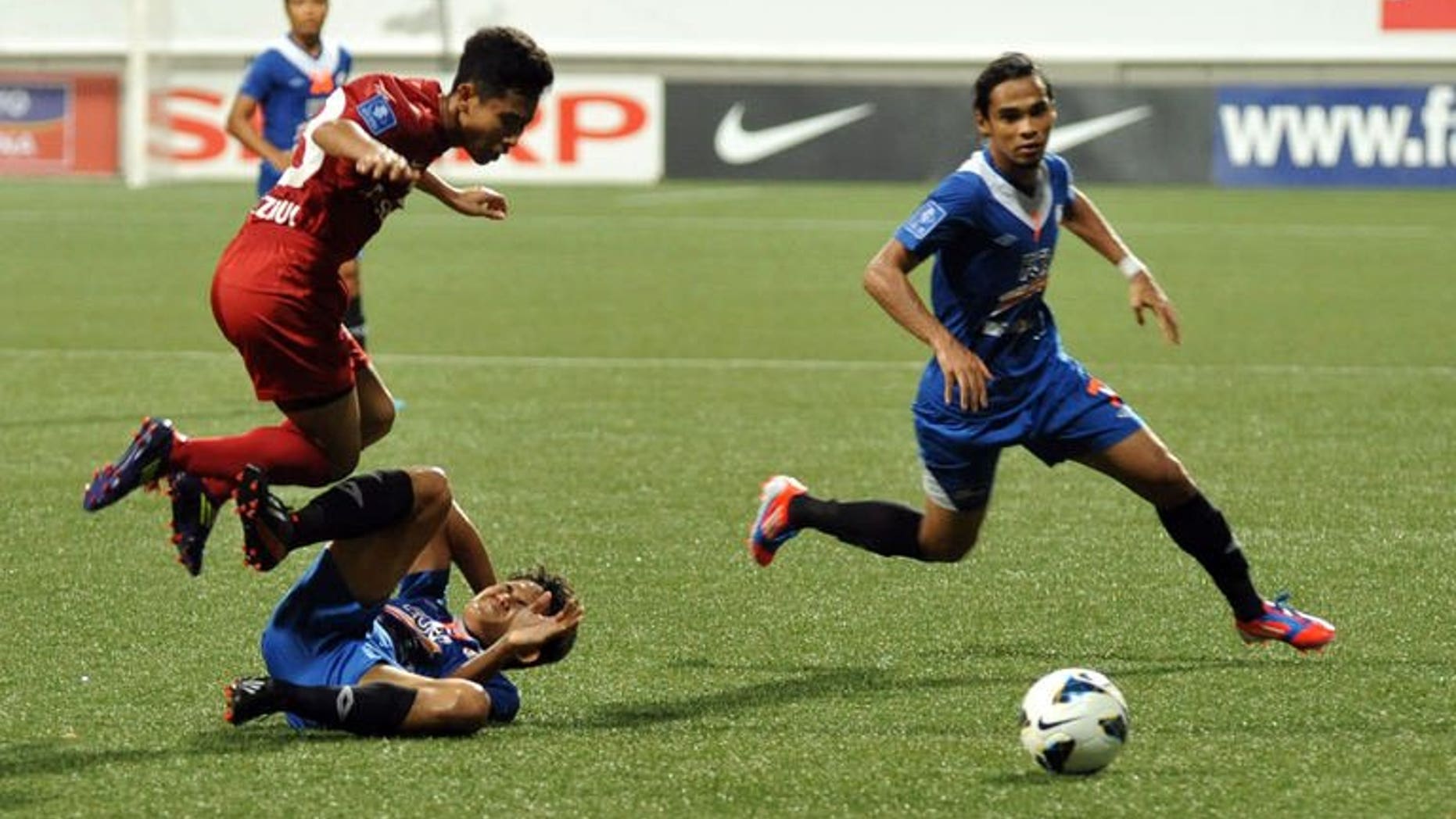 Singapore's LionsXII player Nazrul Nazari (L) leaps over KL Felda United player Mohd Akmal at the Jalan Besar Stadium during the Malaysian Super League in Singapore on July, 2 2013. The LionsXII clinched the Malaysian Super League title Tuesday with a clinical 4-0 win over minnows Felda United, rekindling the city-state's glory days in the competition after a nearly two-decade absence.