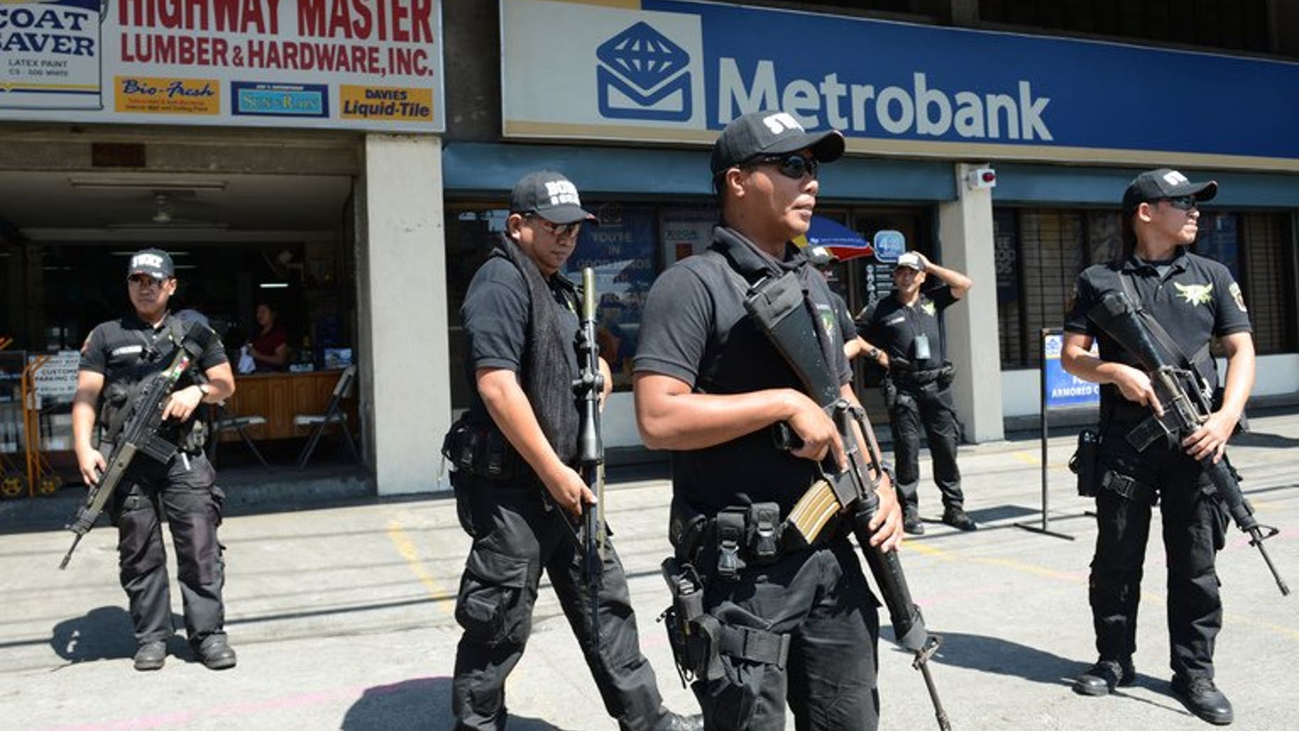 Members of the Pasay City SWAT team patrol in front of a bank in Manila on February 1, 2013. Five young men were shot dead before dawn on Wednesday in a street on the outskirts of the Philippines' main business district, police said.