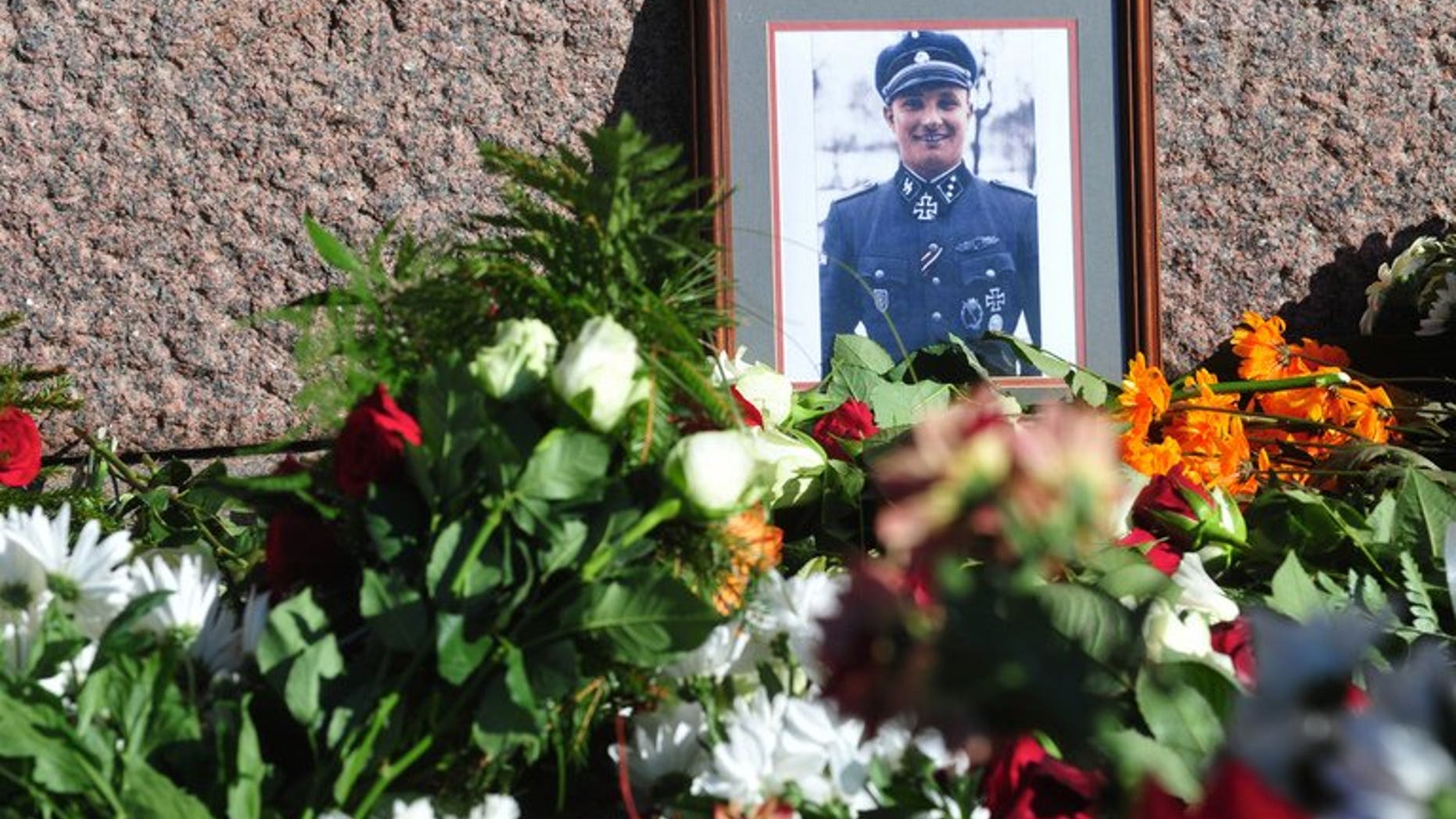 Flowers and a photo of a soldier wearing a uniform with Gestapo insignia and the Iron Cross are laid at the Monument of Freedom in Riga, Latvia where veterans of a force that was commanded by the German Nazi Waffen SS commemorated a key 1944 battle on March 16, 2013. The Simon Wiesenthal Centre Wednesday condemned plans by Latvian nationalists to mark a WWII event that led to a massacre of Jews.