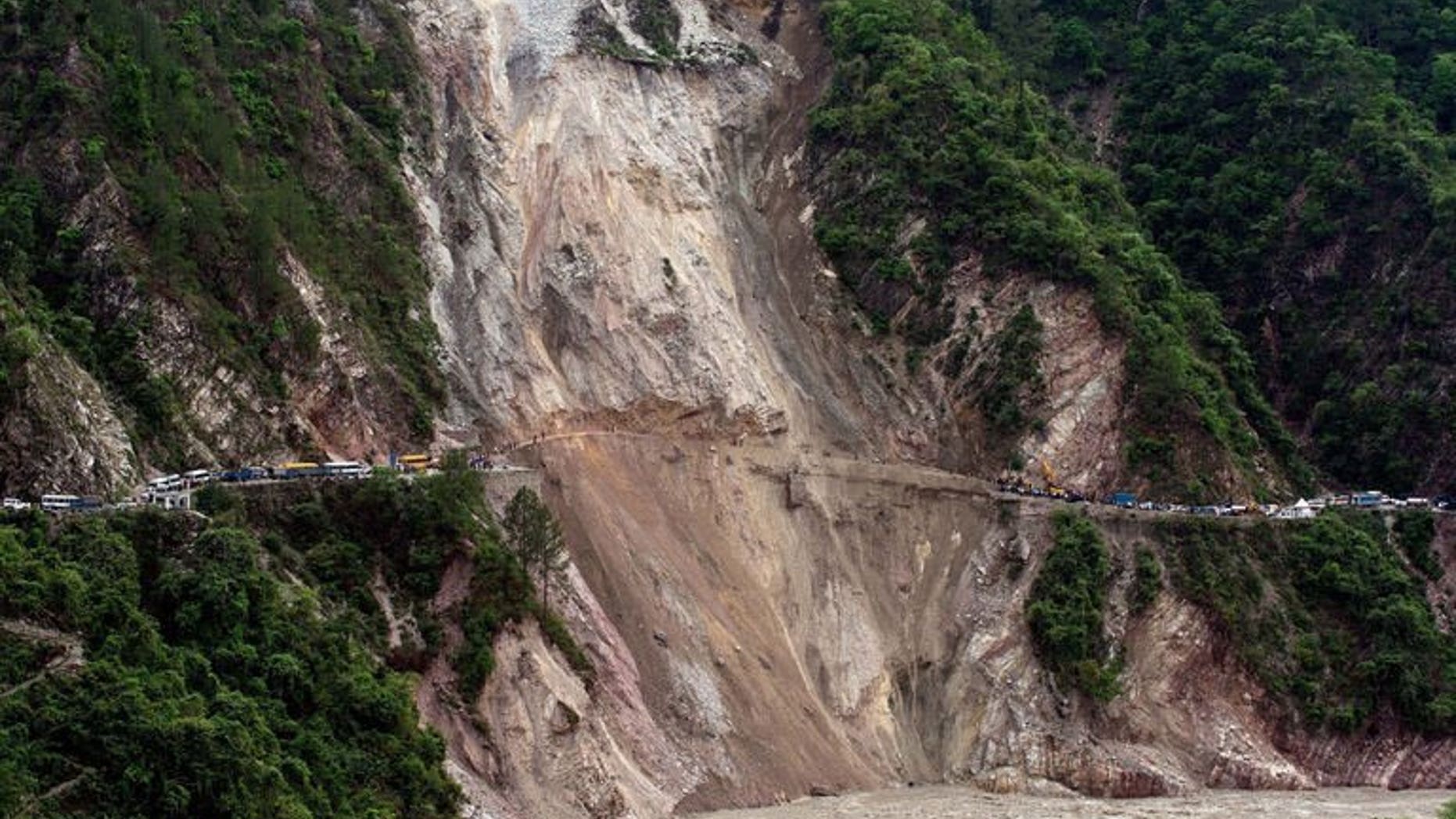 In this picture taken June 25, 2013, vehicles wait on the either side of a road -- linking Rudraprayag and Srinagar -- that was destroyed by a landslide in northern India. Landslides and floods triggered by several weeks of monsoon rains have killed at least 50 people in mainly remote parts of Nepal, a government official said Thursday.
