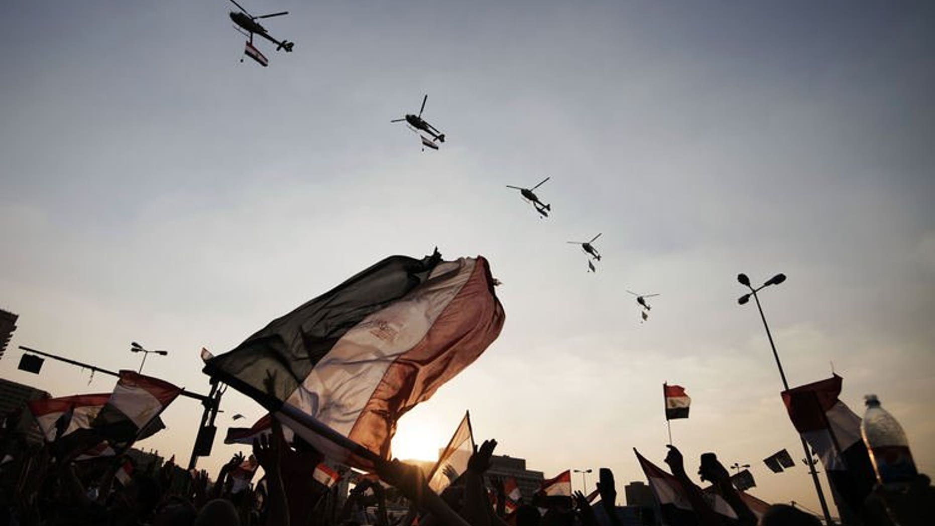 Egyptian people wave the national flag as army helicopters fly above Egypt's landmark Tahrir square on July 4, 2013. Egypt's controversial public prosecutor Abdel Meguid Mahmud said Friday he was to resign, days after being reinstated, citing possible conflicts of interest in future prosecutions.