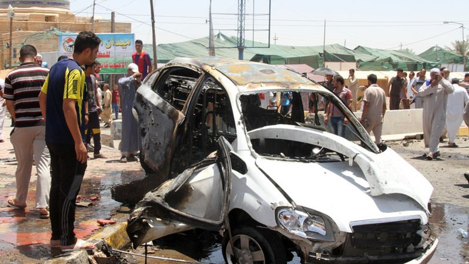 Iraqis inspect the site of a suicide car bomb attack in the Al-Haq square in Samarra, a predominantly Sunni town north of Baghdad, on July 5, 2013. Attacks killed eight people in town squares in Iraq on Friday, including seven who died when a suicide bomber dressed in army uniform set off his car rigged with explosives just before midday prayers.