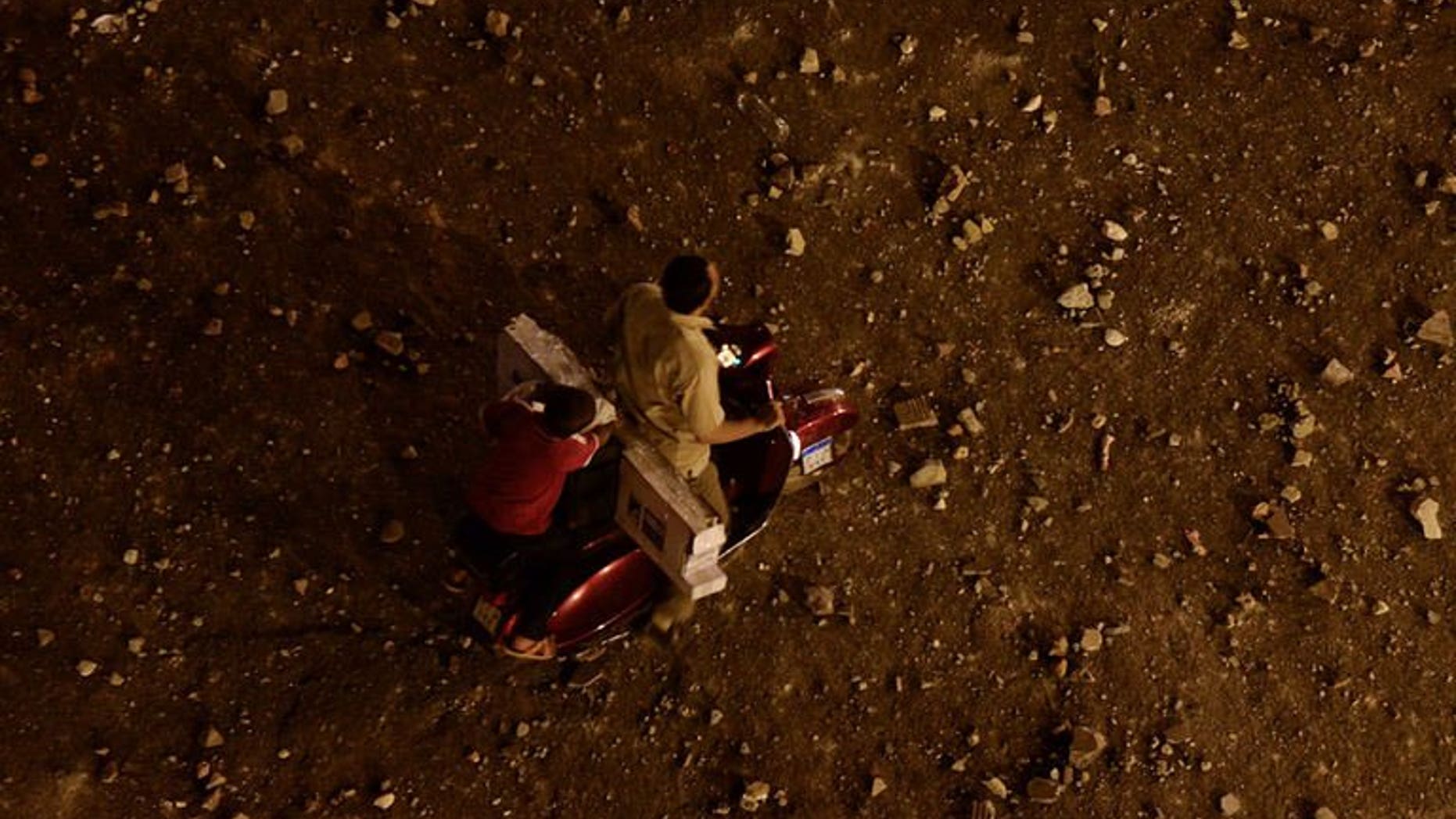 A man and a boy ride a scooter on a road filled with stones following clashes near Egypt's Tahrir Square on July 5, 2013 in Cairo. Armed to the teeth, hundreds of Islamists left a trail of destruction when they tried to pass through a normally quiet Cairo neighbourhood, only to be confronted by residents who tried to stop them reaching Tahrir Square.