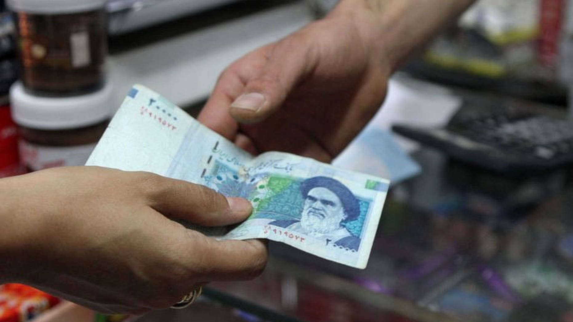 An Iranian woman pays with a 20000 rial banknote in Tehran on September 30, 2012. Iran's central bank on Saturday drastically devalued the national currency's fixed subsidised rate against the dollar, as the Islamic republic struggles to shore up its faltering economy.
