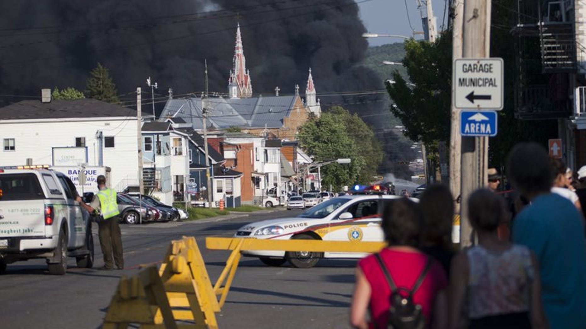 Residents watch rising smoke after a freight train loaded with oil derailed in Lac-Megantic in Canada's Quebec province on June 6, 2013. At least 80 people are missing in the small Canadian town after the accident, a firefighter told AFP.