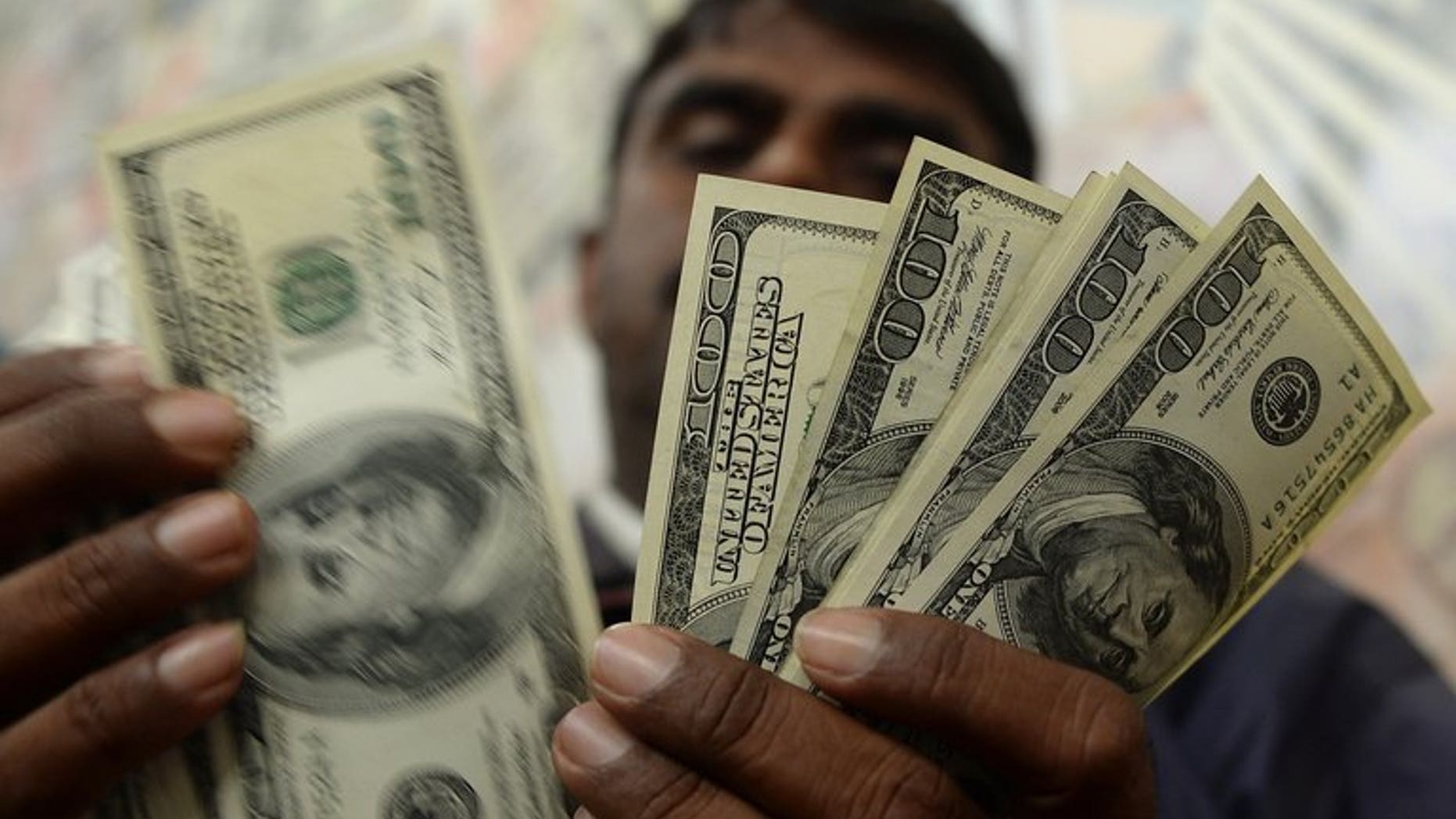 An Indian man counts US dollar notes at a currency exchange shop in Mumbai on June 26, 2013. India's rupee fell to a new record low against the dollar, as the greenback was boosted by another set of strong US economic data.