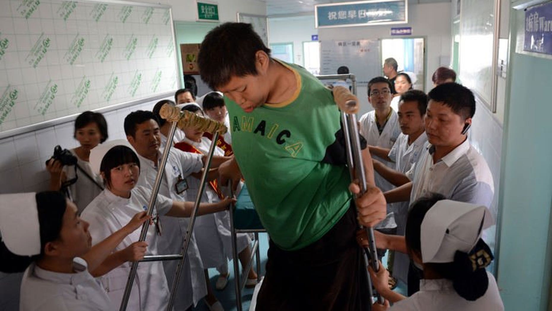 Wang Fengjun gets off a specially designed chair at a hospital in Zhengzhou, central China, on July 6, 2013. Wang, who is among the world's tallest living people, has been hospitalised for a hip replacement.