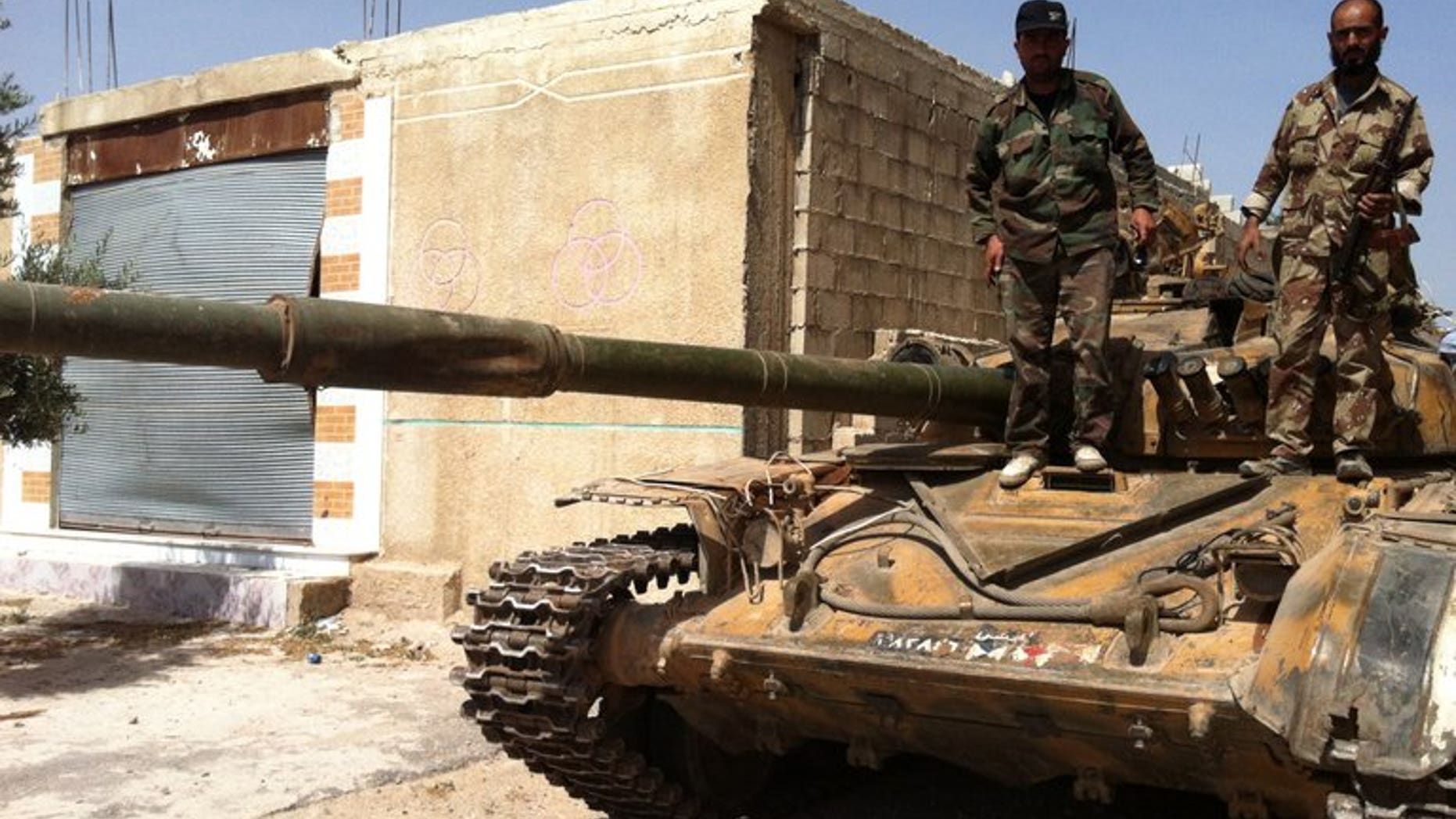 Syrian army soldiers stand on a tank in the village of Buweida, in Homs province on June 8, 2013. Syrian troops have advanced into the rebel-held Khaldiyeh district of central Homs, with shelling intensifying as forces battled for a 10th day in the area, activists and an NGO said.