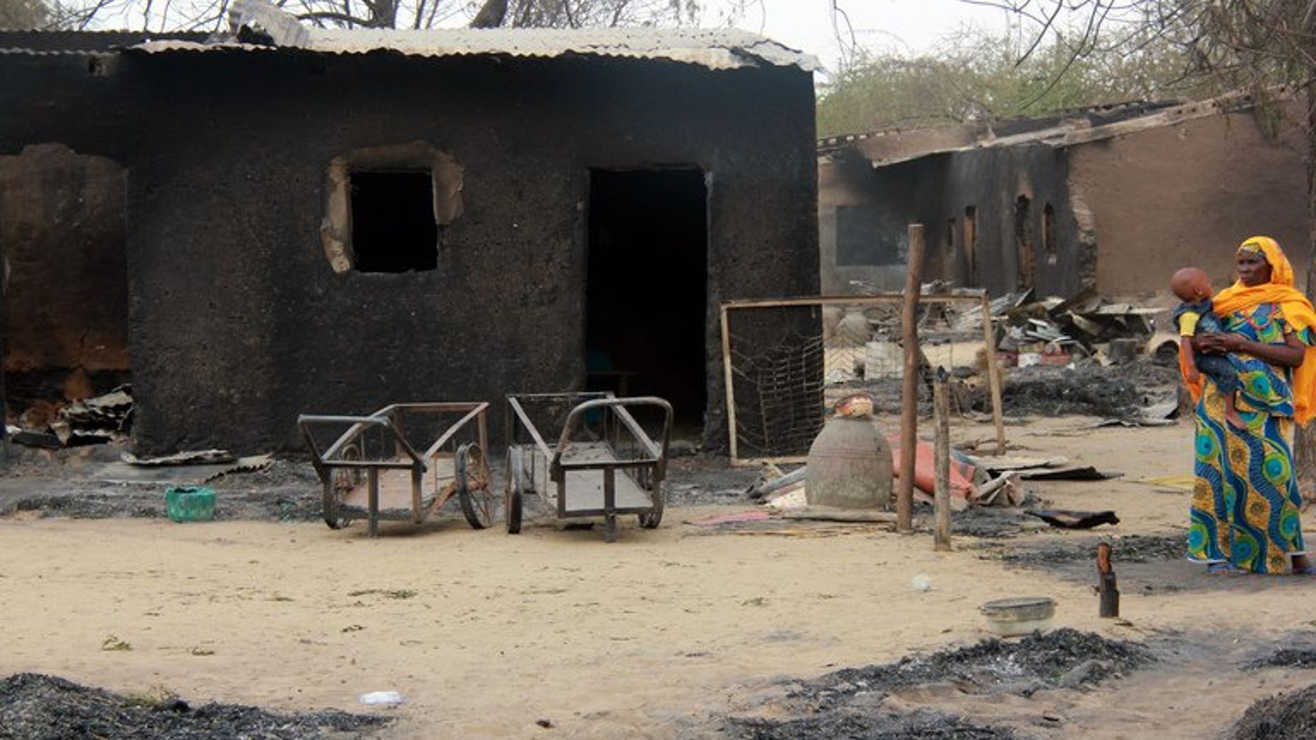 A woman stands near her burnt house in Nigeria's remote northeast town of Baga on April 21, 2013 after two days of clashes between officers and members of the Nigerian-based Islamist extremist group Boko Haram. The group is to be banned in Britain under anti-terror laws, the British interior ministry announced on Monday.