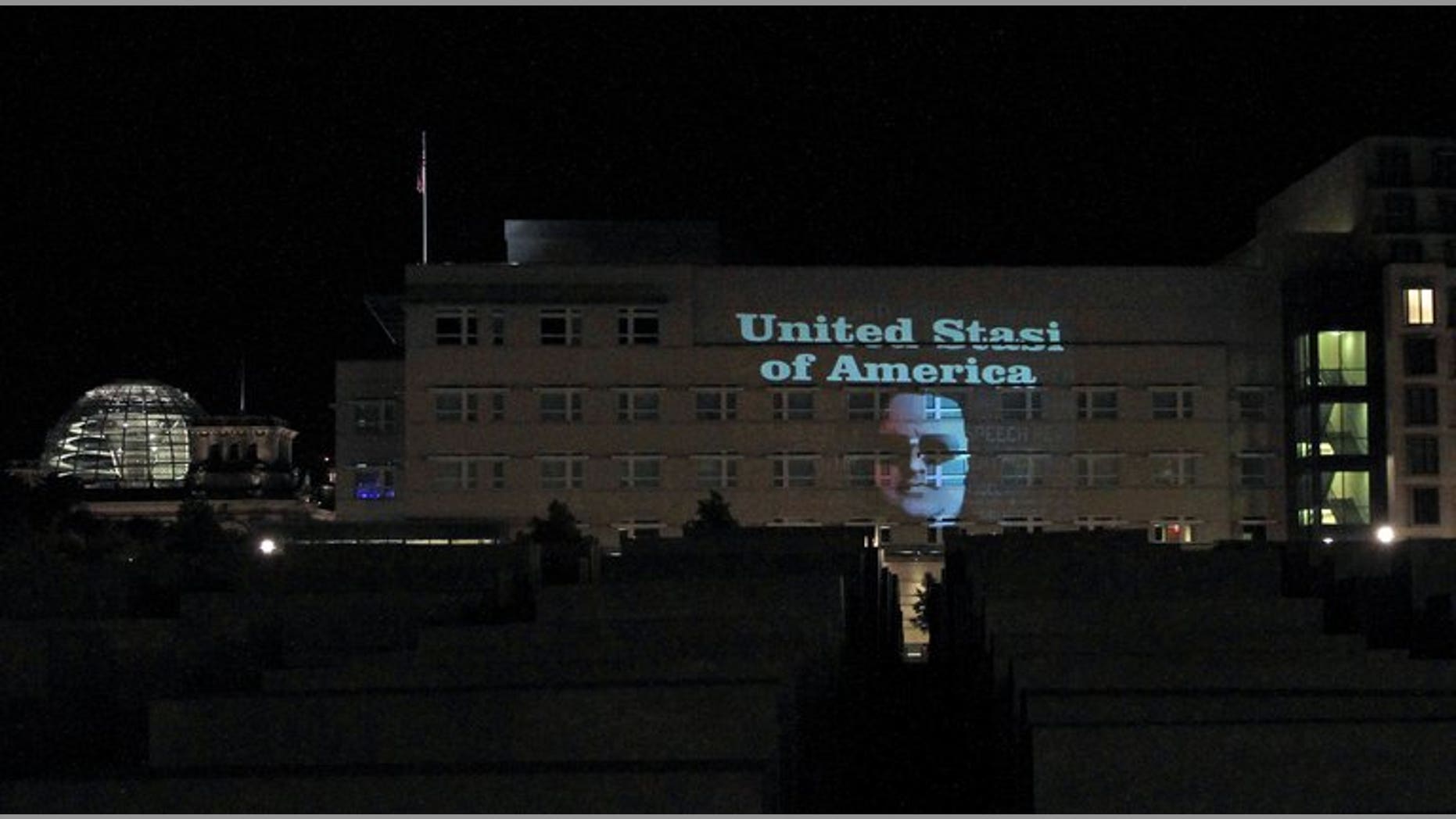 The message "United Stasi of America" and the face of Megaupload founder Kim Dotcom are displayed on the facade of the US embassy in Berlin on the night of July 8, 2013. The reference to the former communist Staatssicherheit or Stasi police was beamed at night onto the US mission by German artist Oliver Bienkowski, in collaboration with Internet tycoon and online activist Kim Dotcom.