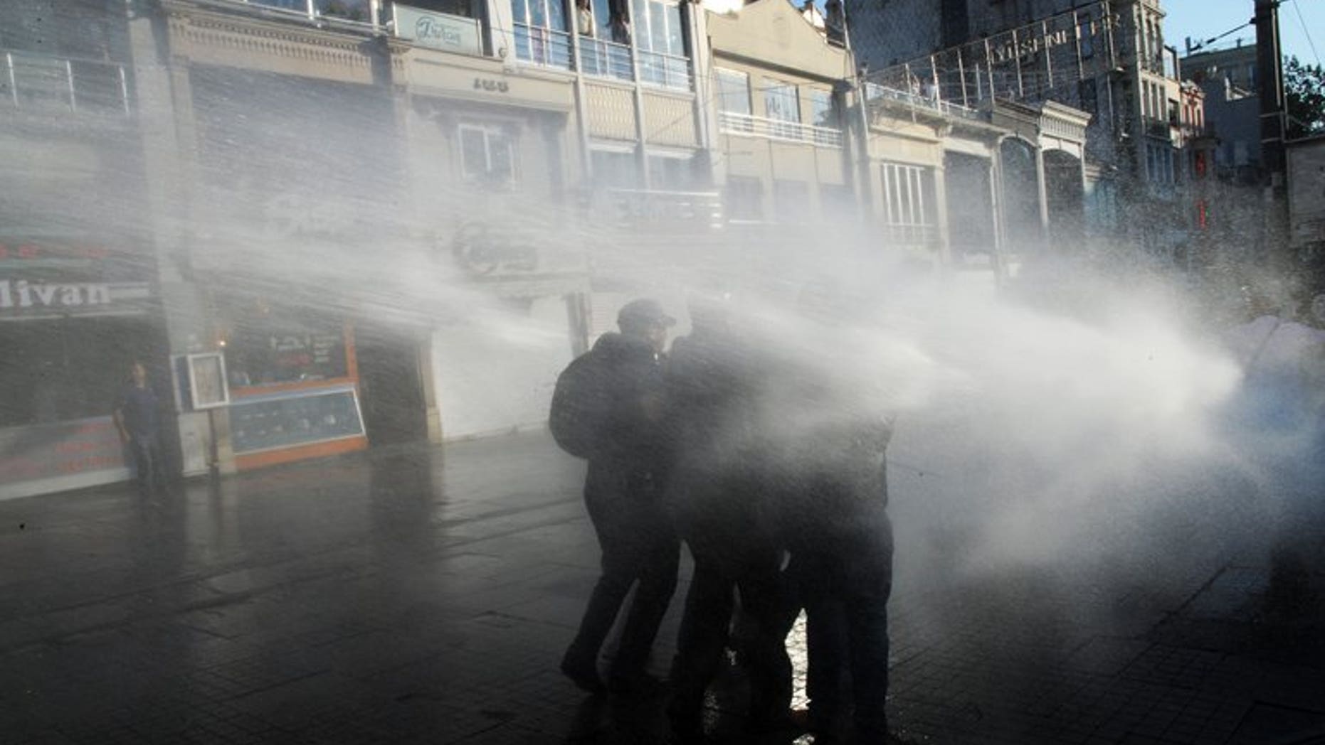 Turkish protesters take cover from a water cannon during clashes with police on Istiklal Avenue in Istanbul, on July 8, 2013. A 19-year-old university student who was hurt during anti-government protests that rocked Turkey last month has died from his injuries, bringing the death toll in the unrest to five, according to local media reports.