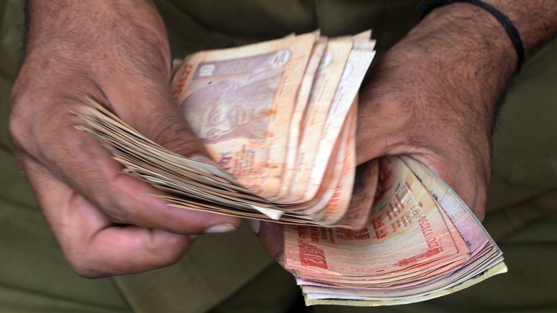 A man counts currency notes in Mumbai on June 20, 2013. Indian companies will be "severely" hit by the rupee's plunge to record lows due to their hefty foreign debts, the country's top credit ratings agency Crisil Research warned Wednesday.
