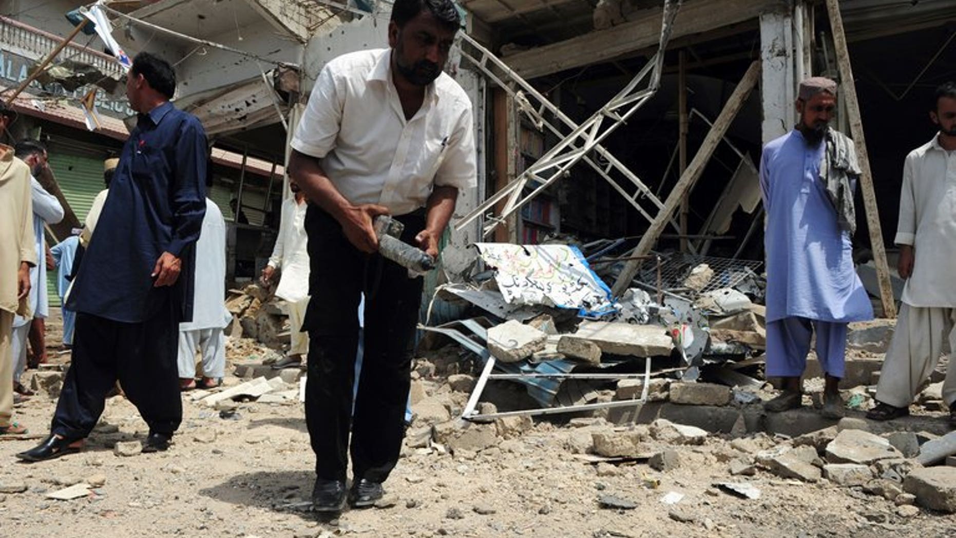 A Pakistani bomb disposal expert examines the site of an explosion in Karachi, on May 11, 2013. A bomb targeting one of Pakistani President Asif Ali Zardari's senior personal security officers has killed at least three people in Karachi.