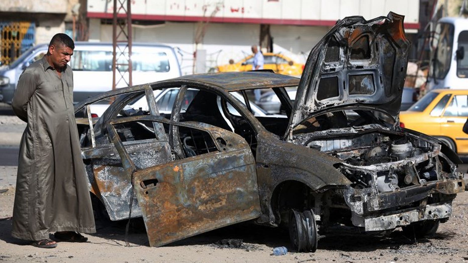 An Iraqi man inspects a burnt-out vehicle at the site of a car bomb explosion in the Hurriyah area of Baghdad, on July 3, 2013. Violence in Iraq is on the rise and could lead towards civil war, the head of the UN human rights mission warned on Wednesday.