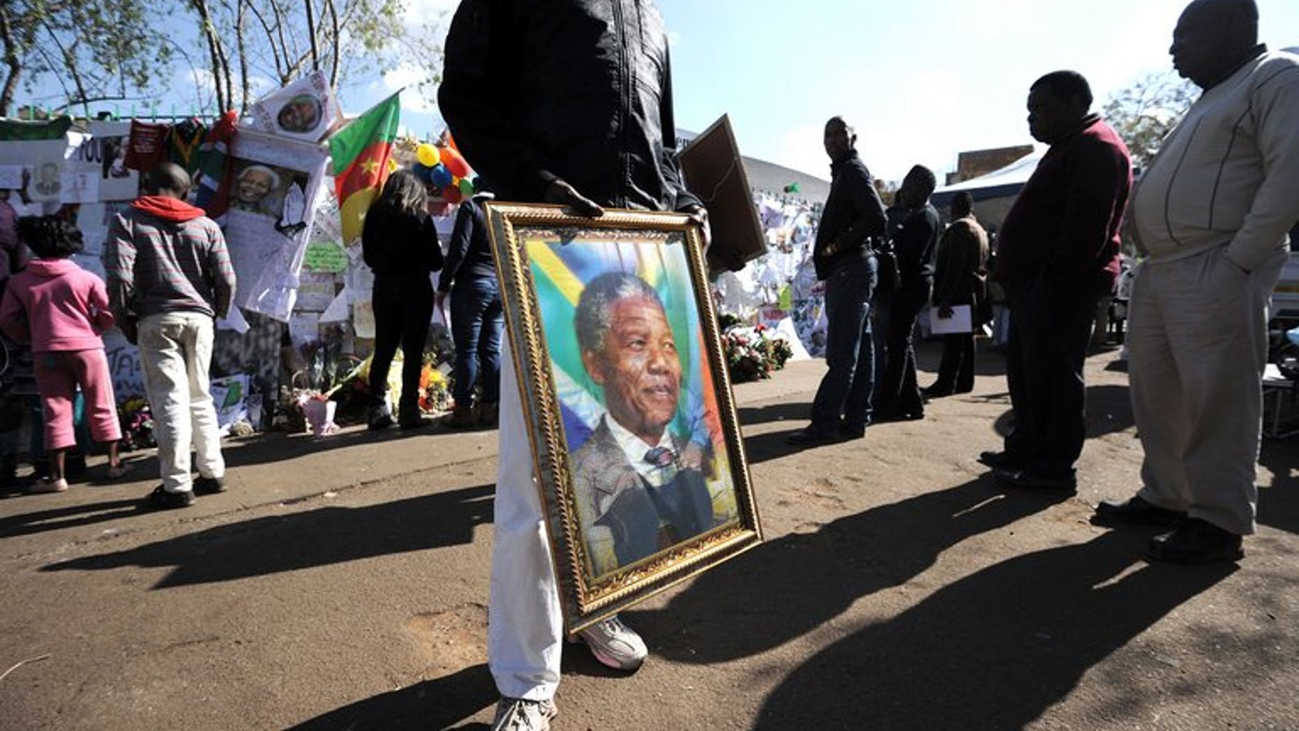 A man sells a portrait of former Nelson Mandela on Thursday outside the MediClinic Heart Hospital in Pretoria. Mandela "continues to respond to treatment" but is still in a critical condition in hospital, South Africa's presidency said Thursday.