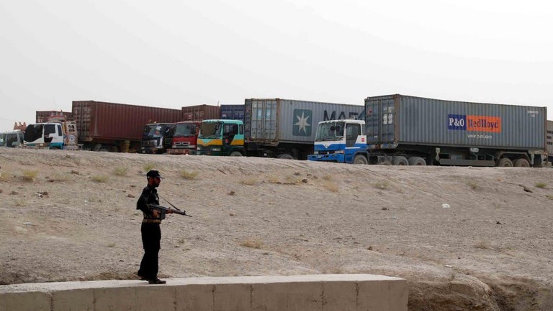 A Pakistani security serviceman stands guard beside container trucks parked at the border town of Chaman on July 27, 2012. A bomb explosion on Thursday killed at least two people and wounded eight others including four paramilitary Frontier Corps (FC) officials in a southwestern Pakistani town near the Afghan border, officials said.