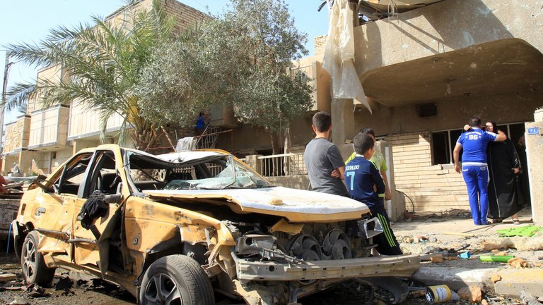 Iraqis sit on a damaged car after a car bomb explosion near a Shiite Islamic center in the Baghdad neighbourhood of Qahira on March 29, 2013. A car bomb followed by a suicide bombing targeting people mourning a Shiite man killed 10 people and wounded 22 in Iraq on Thursday, police and a doctor said.