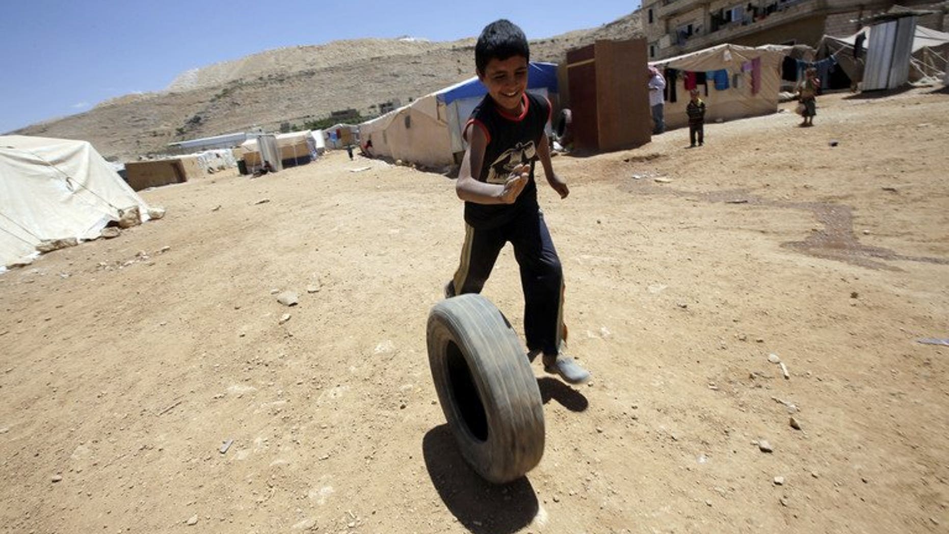 A young Syrian boy, who fled with his family after recent violence in Qusayr, plays with a tyre at the Arsal refugee camp on June 14, 2013 in Lebanon. A majority of Lebanese believe the influx of Syrian refugees in their country threatens national security, Norway's Fafo research foundation said in a report obtained on Thursday by AFP.