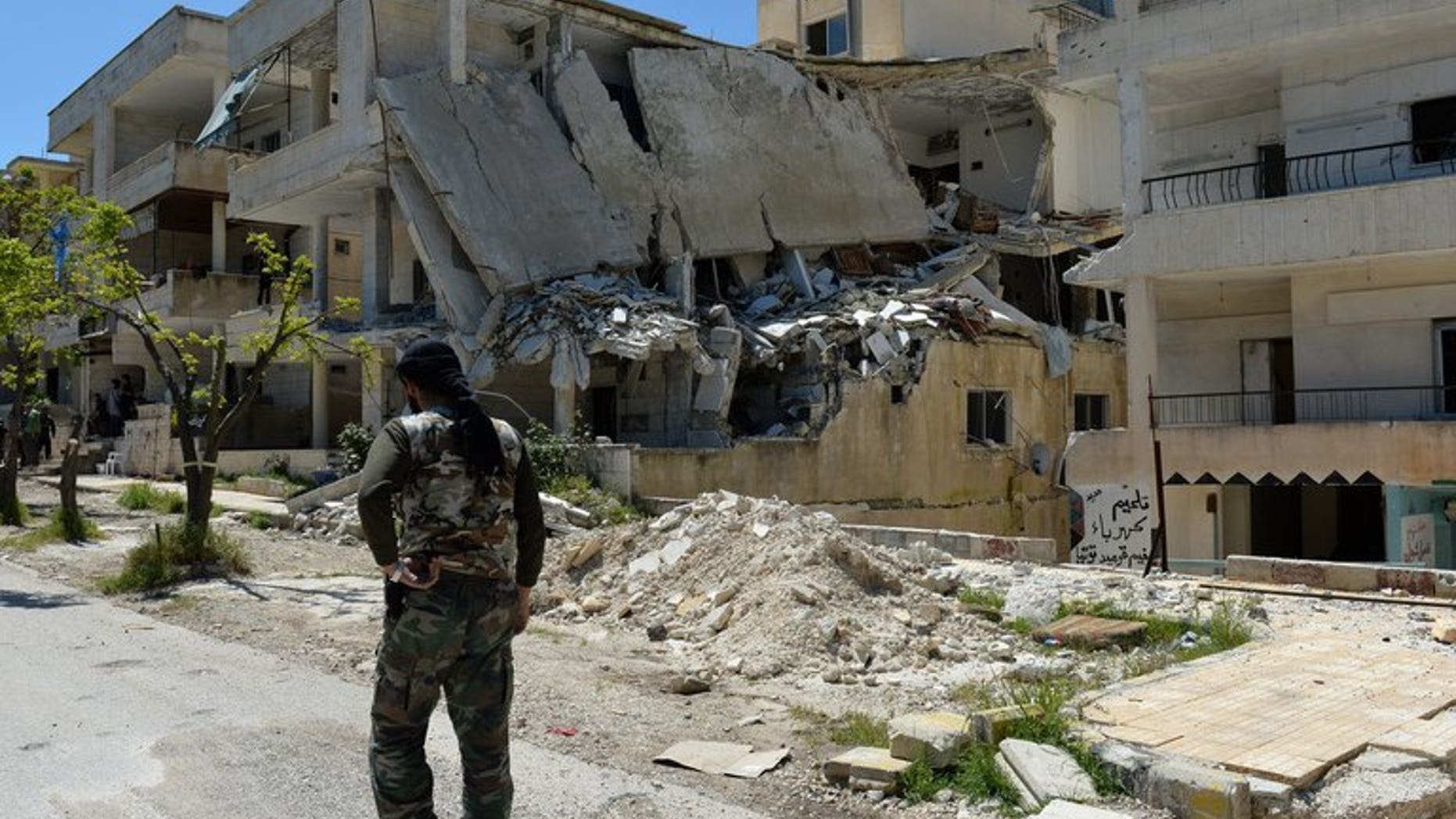 A Syrian rebel walks past a destroyed building in Salma in the coastal province of Latakia on April 26, 2013. An Al-Qaeda front group operating in Syria has killed a rebel chief in a firefight in the province, a monitoring group said.