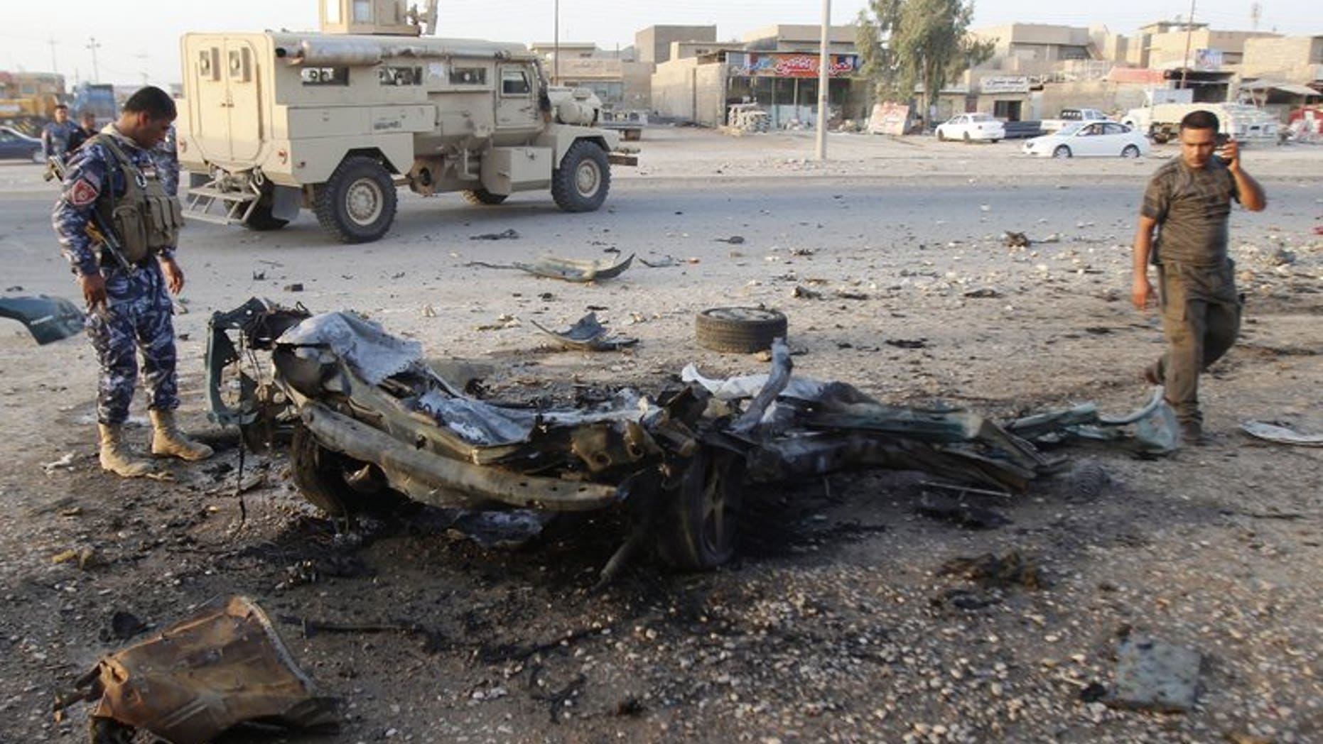 An Iraqi soldier (L) inspects the wreck of a car bomb after it exploded in the military zone of the northern Iraqi city of Kirkuk on July 11, 2013.