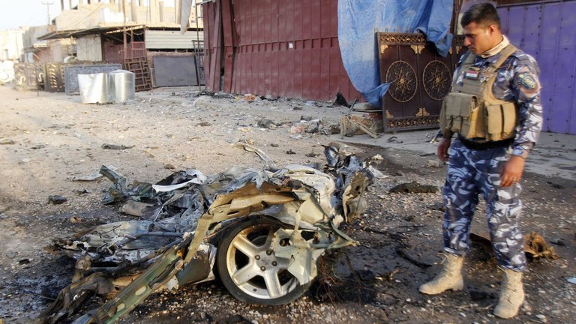 An Iraqi soldier inspects the wreck of a car bomb in the northern Iraqi city of Kirkuk on July 11, 2013. A suicide bomber targeting a cafe in the town killed at least 18 people and wounded 28, police and medical sources said.