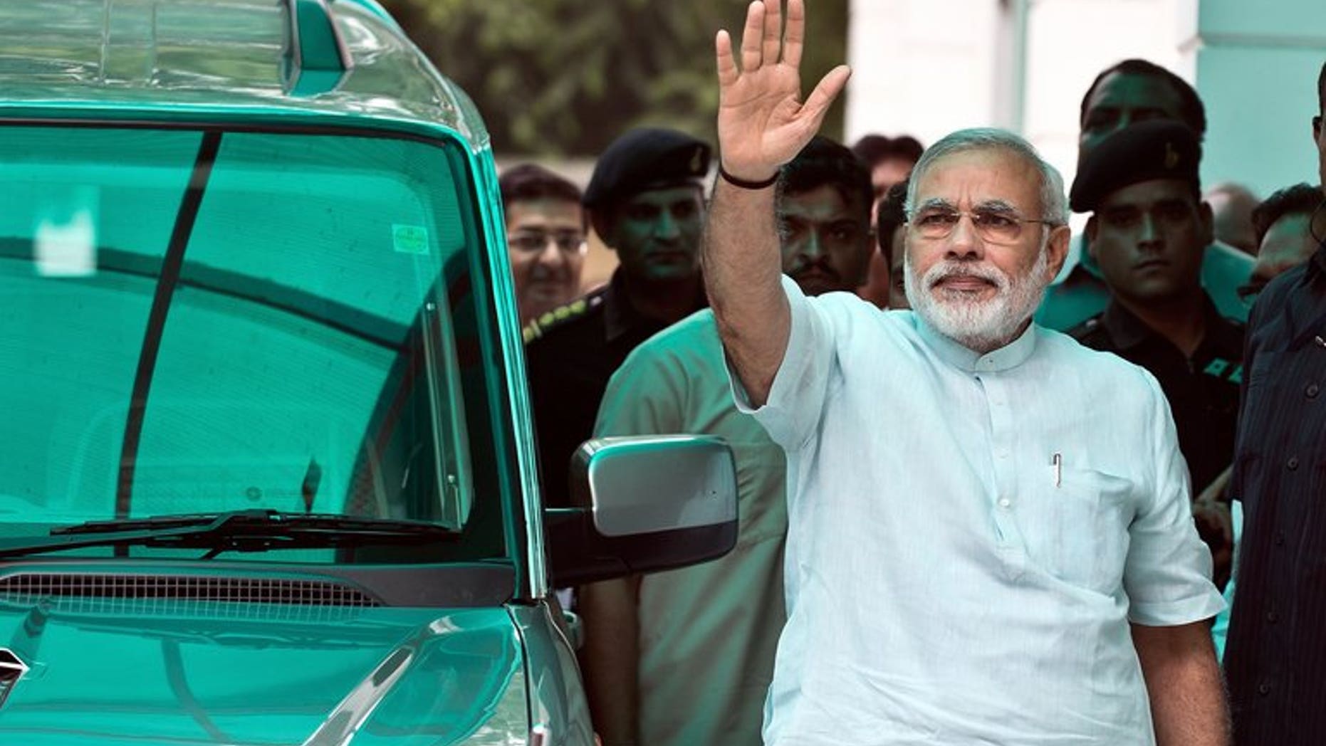 Bharatiya Janata Party (BJP) leader Narendra Modi waves on his arrival at party headquarters in New Delhi, on July 8, 2013. Modi -- seen as the key opposition challenger in 2014 elections -- has said he meant no offence when he compared victims of anti-Muslim violence to puppies run over by a car.