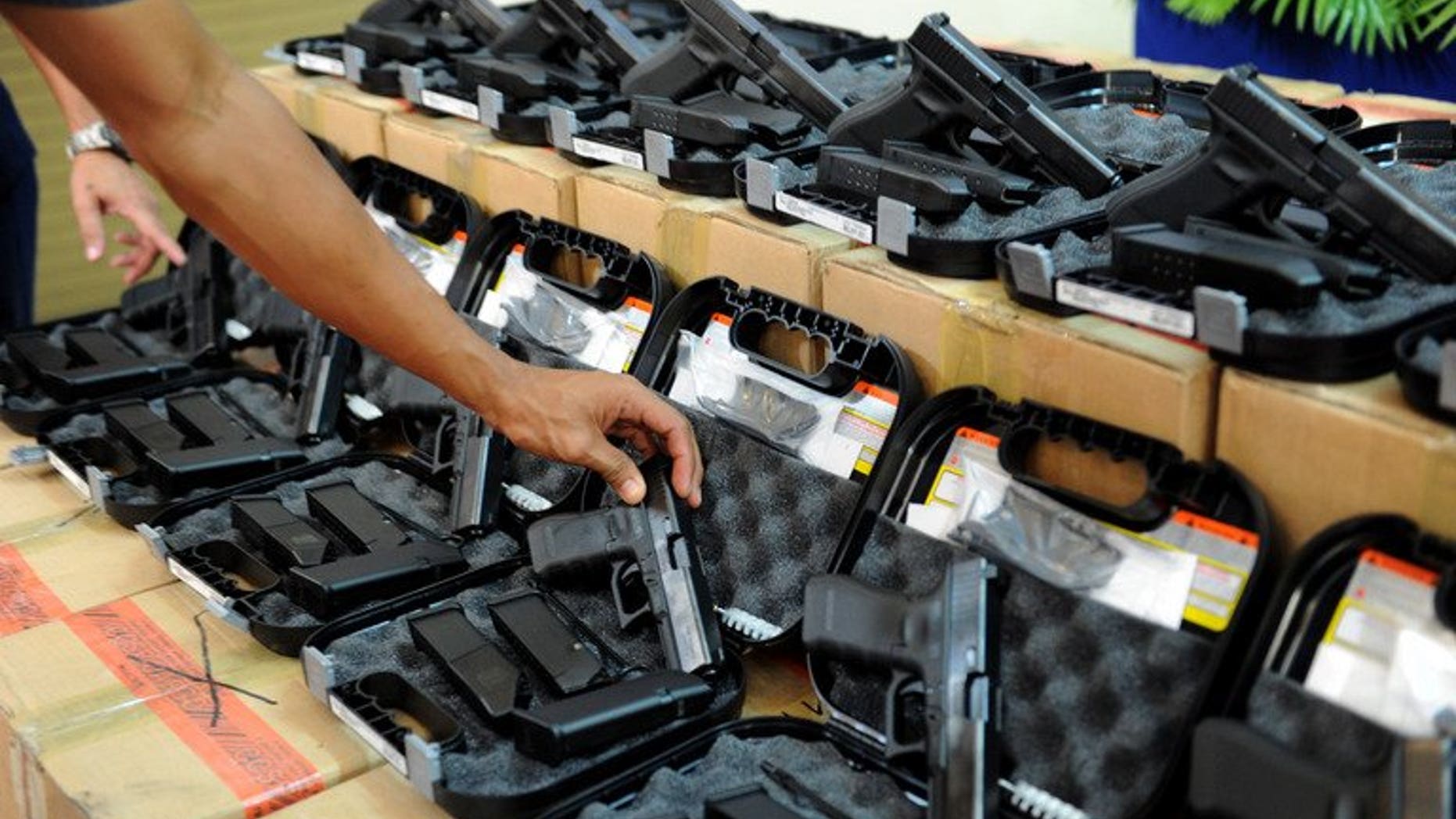 A Philippine police officer inspects pistols during a ceremony in Manila, on July 2, 2013. The Philippines is to investigate a group of police officers who were allegedly filmed executing a criminal, the government's human rights commission said Saturday.