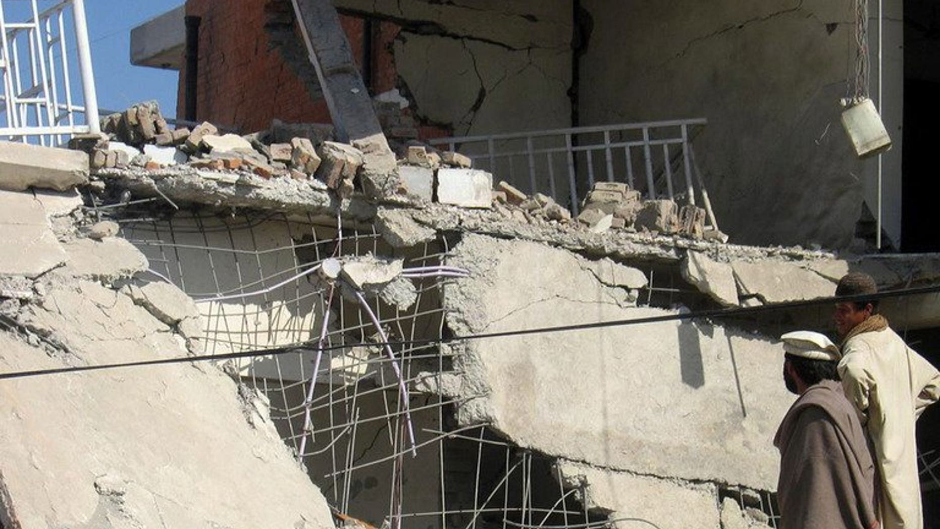 Pakistani residents look at the damaged building after an explosion in Wana, the main town of South Waziristan tribal district on February 18, 2009. The Pakistani Taliban have banned tight or see-through clothing for men, threatening to impose a fine and shutter businesses selling the items, traders from the country's restive tribal belt said Saturday.