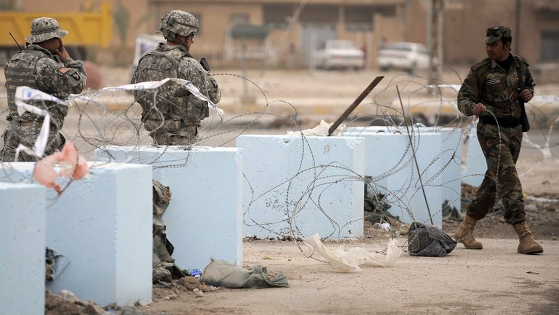 An Iraqi policeman (R) clears the way for US soldiers, near the border with Iran, on January 30, 2009. Clashes between Iraqi border police and gunmen who crossed from Syria into western Iraq killed a policeman and wounded five on Saturday, an officer said.